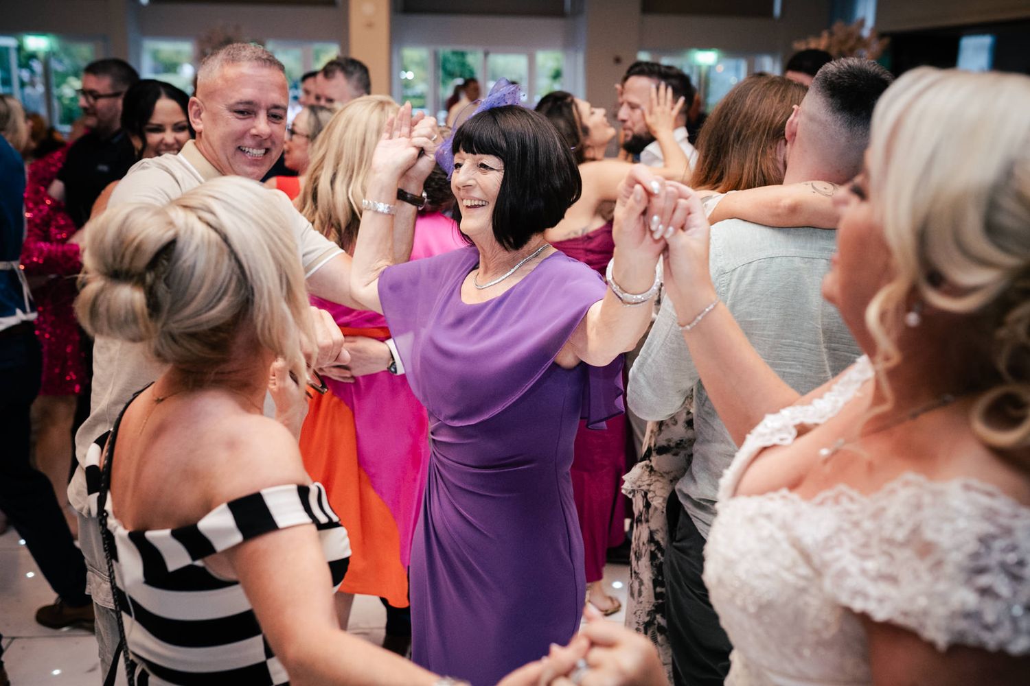 People enjoying a lively celebration on the dance floor decorated with twinkle lights and colorful party atmosphere.