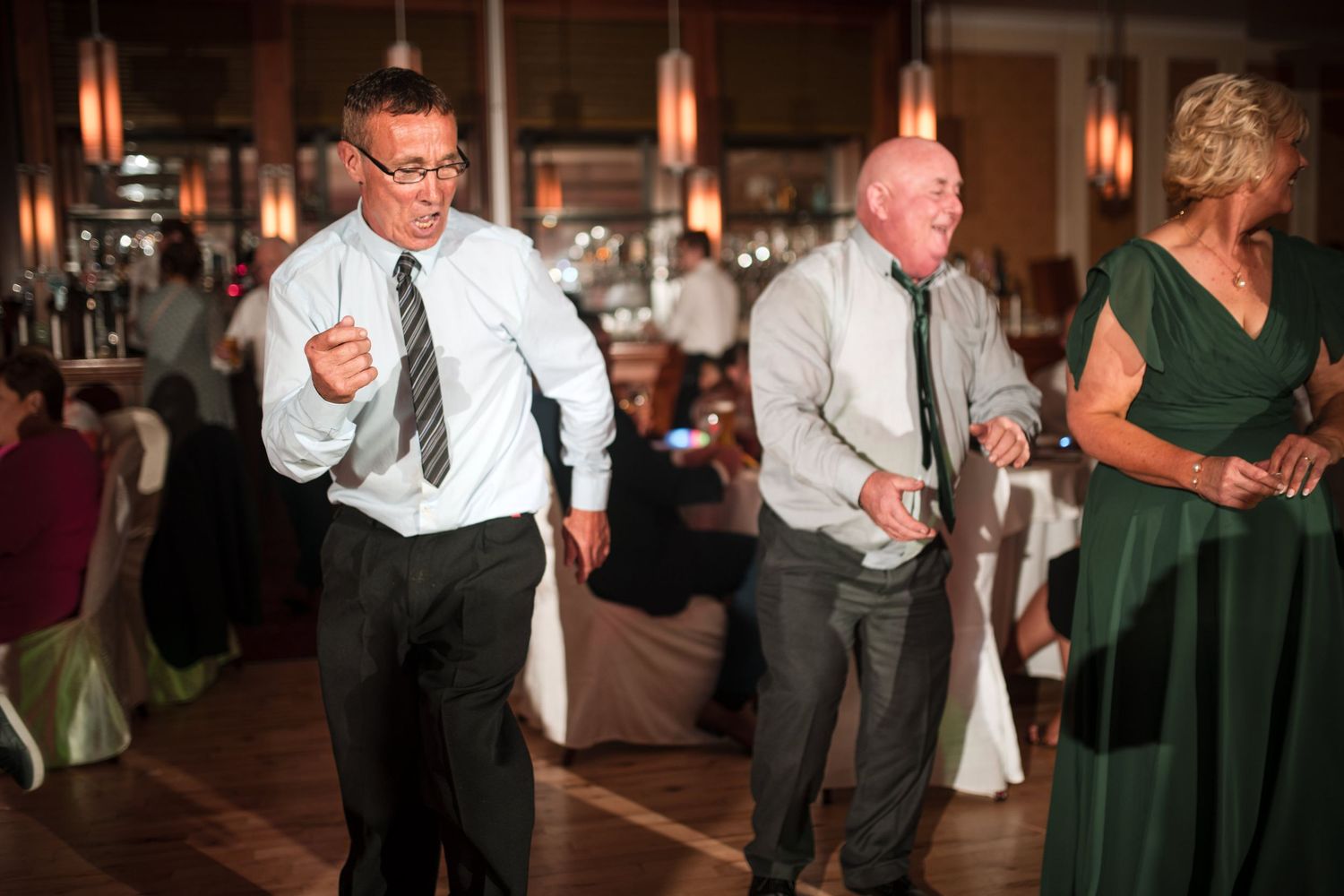 Reception guests dancing and mingling on a ballroom dance floor at an evening celebration event.