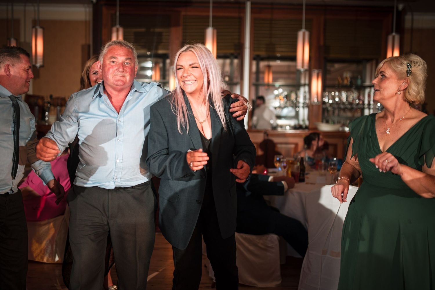 People enjoying themselves on a dance floor with warm lighting at an indoor celebration event.