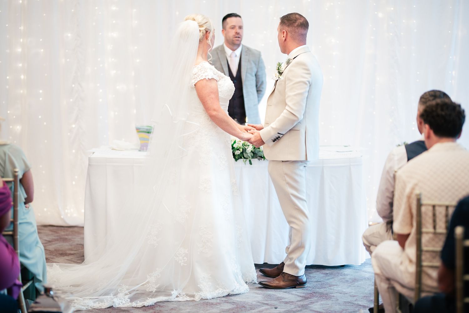 A couple shares an intimate moment together during their wedding ceremony against a white background.