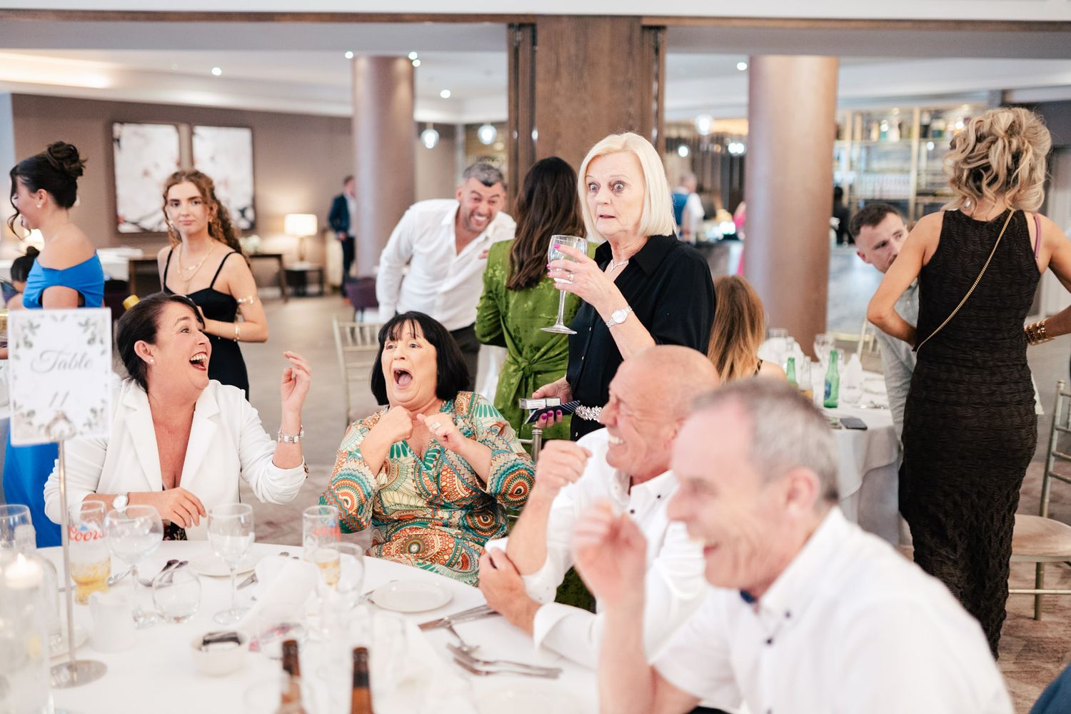 Wedding guests sharing laughter and conversation around elegant tables at a reception dinner.