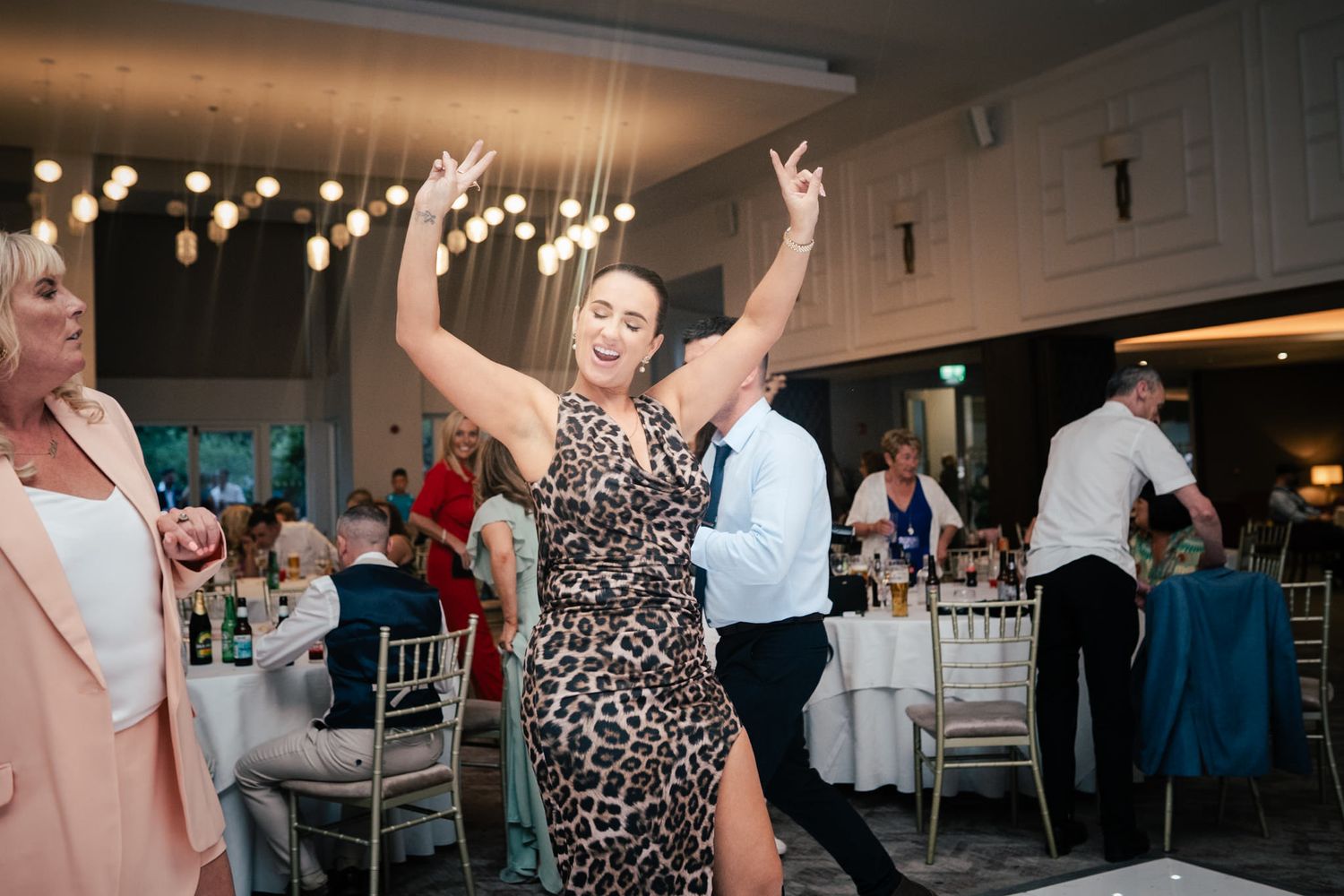 People enjoying a lively party atmosphere with hanging string lights and decorative elements in an indoor venue.