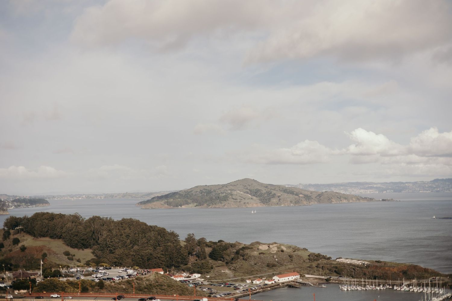 An aerial view of Angel Island and San Francisco Bay on a cloudy day with hillsides in the background.