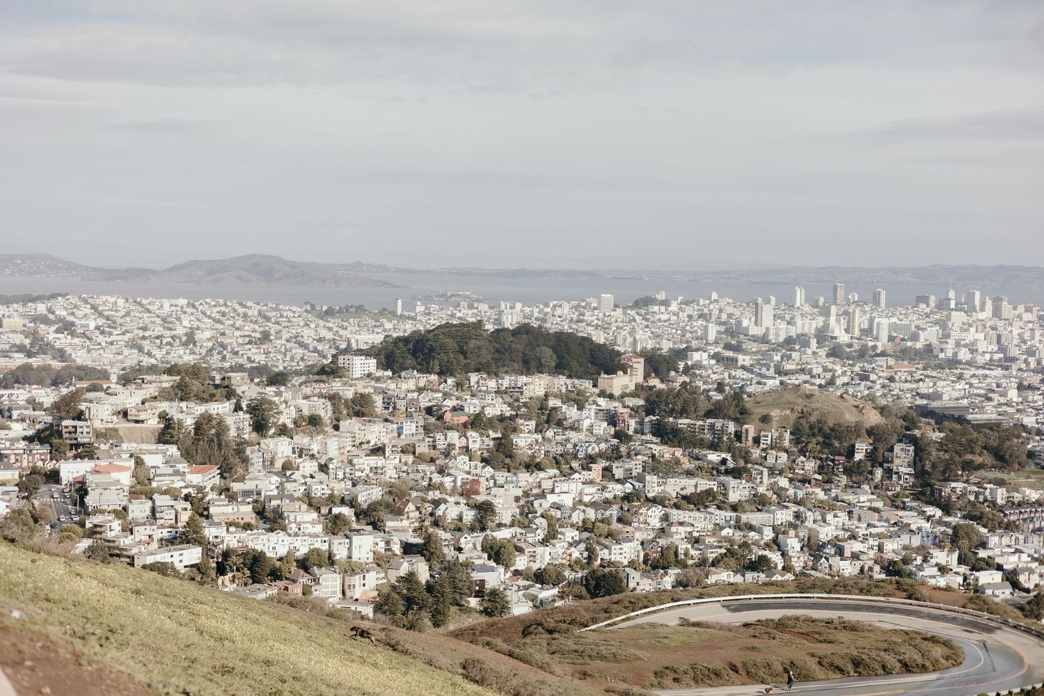 Aerial view of San Francisco cityscape with dense urban buildings and hills under overcast sky.