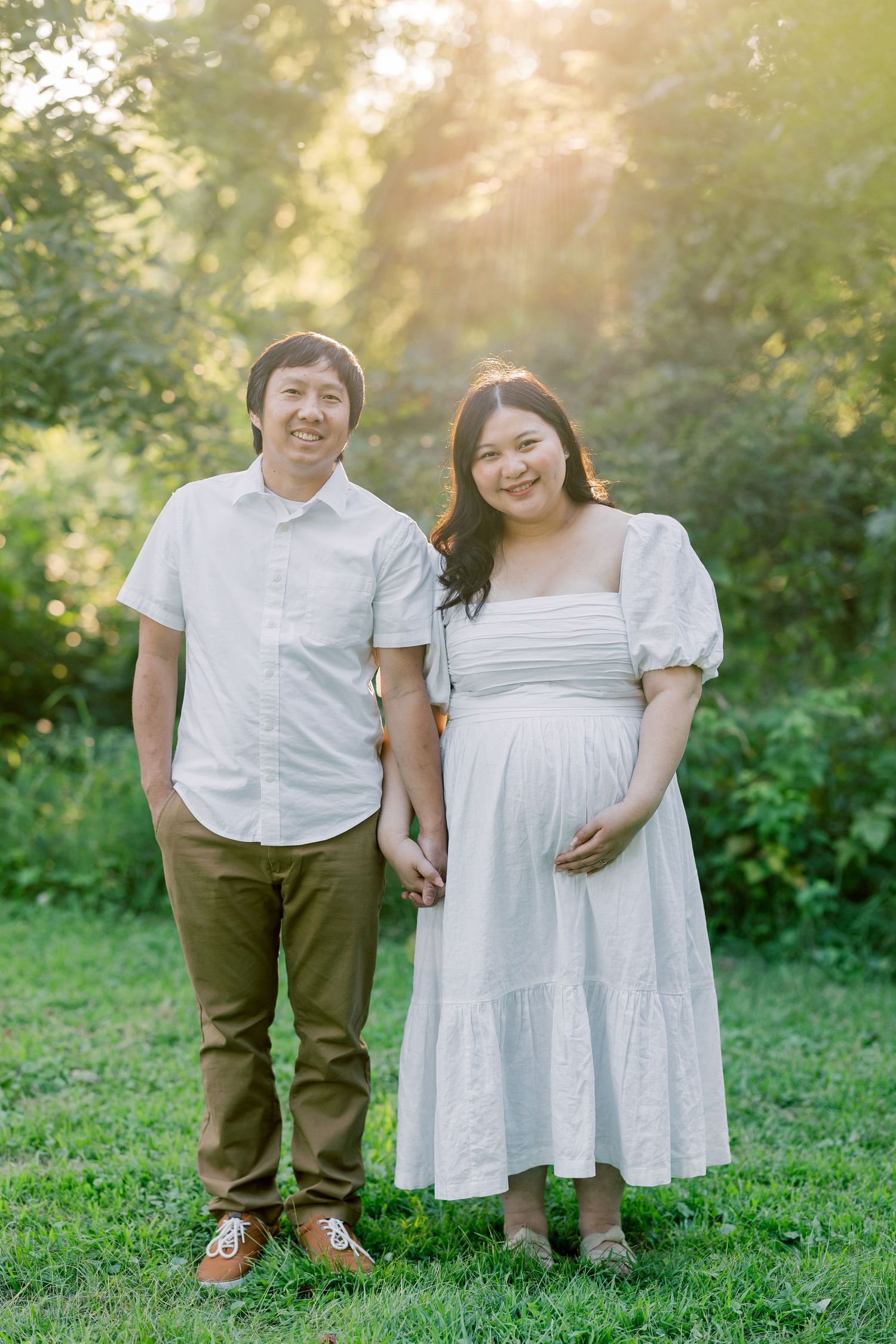 A couple standing together in a sunlit garden during golden hour.