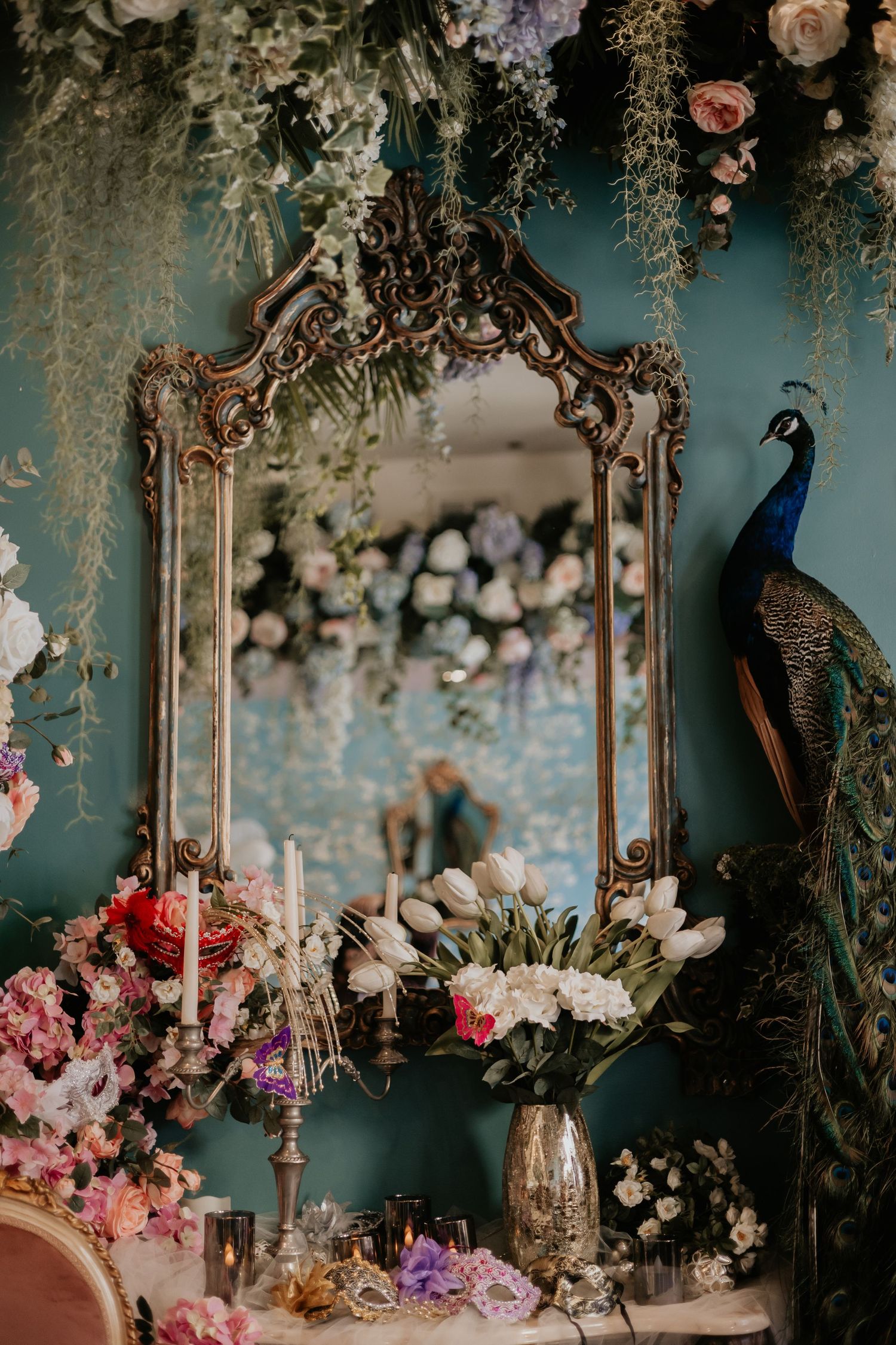 Ornate vintage mirror adorned with flowers and a peacock in a romantic setting.
