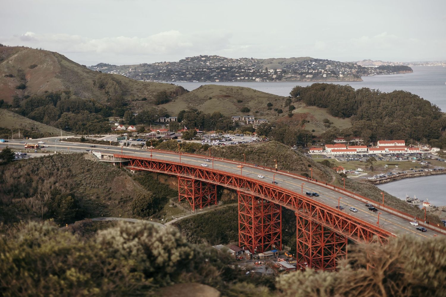 Red Golden Gate Bridge stretching across the bay with coastal hills in background.