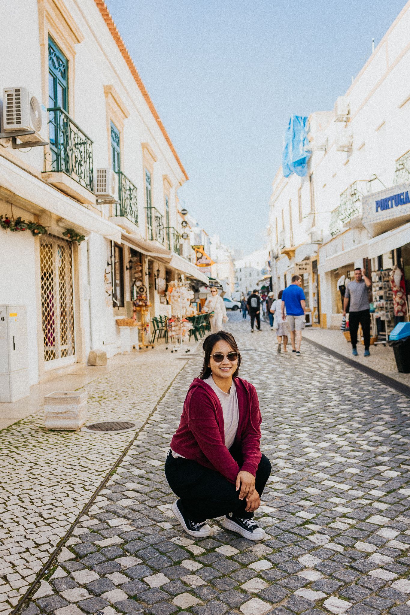 Picturesque cobblestone street in Portugal with traditional white buildings and wrought iron balconies.