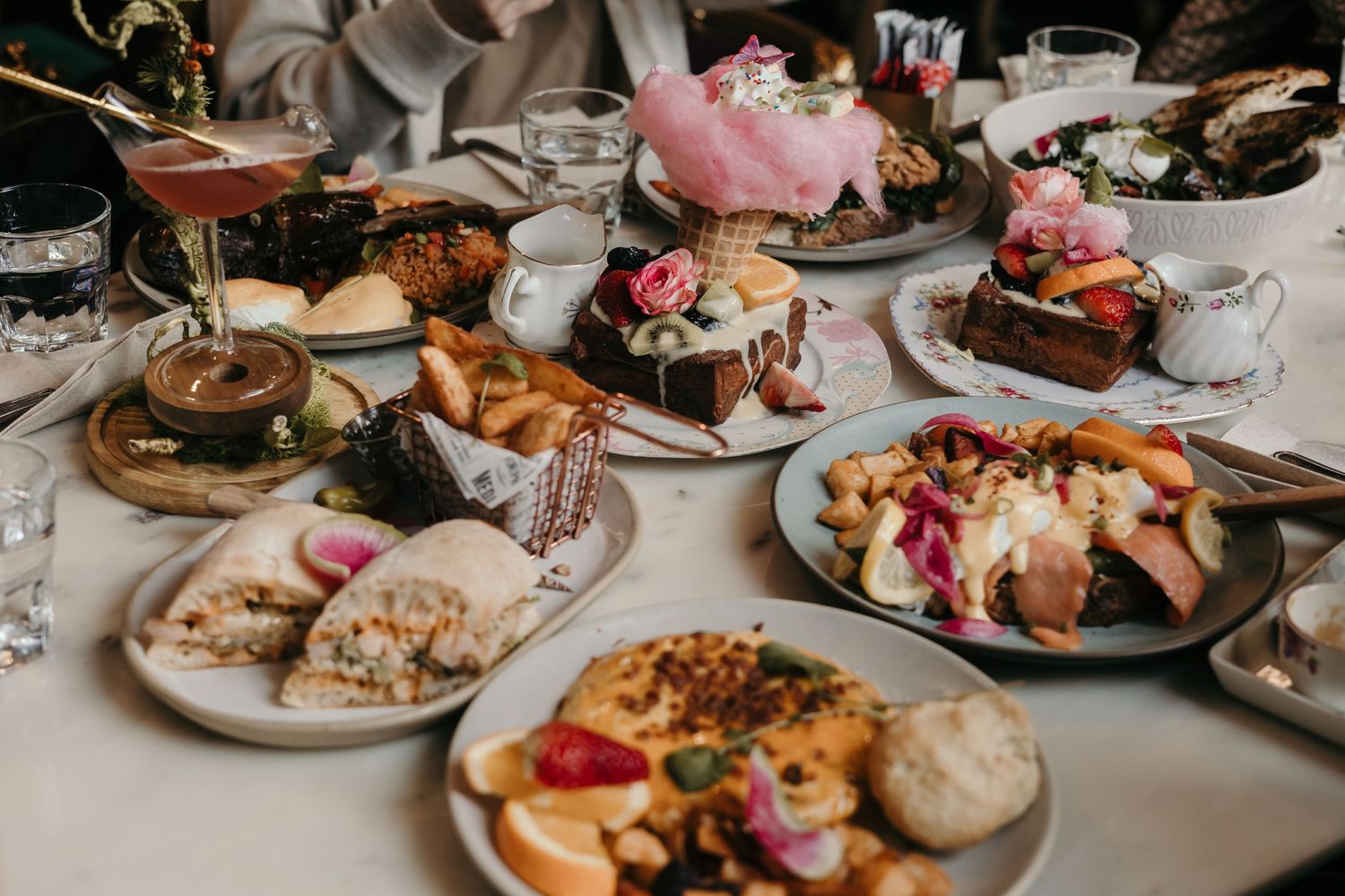 Elegant brunch spread with various pastries and dishes on white plates.