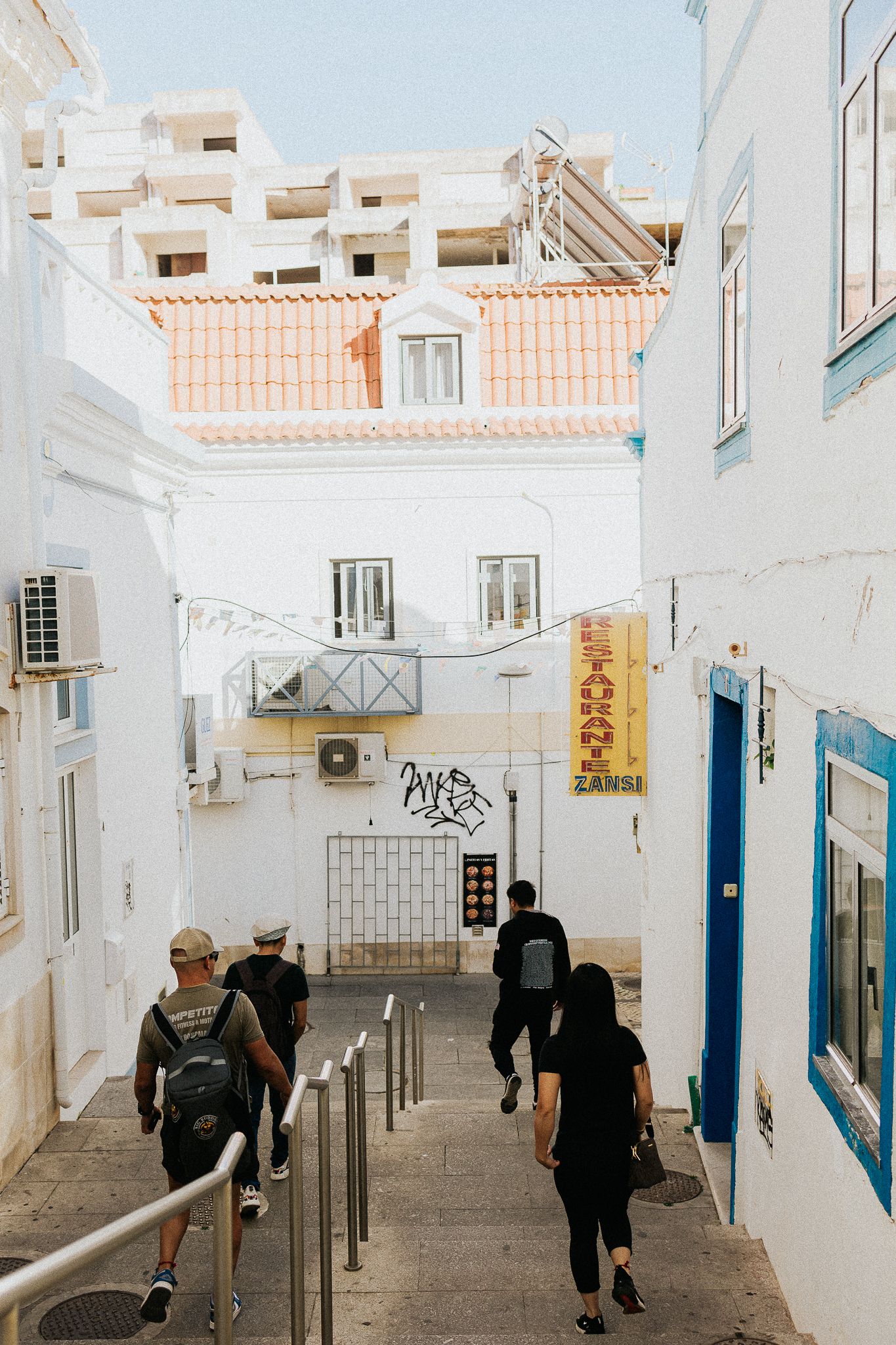 White stairway passage between buildings with blue accents and people walking downstairs.