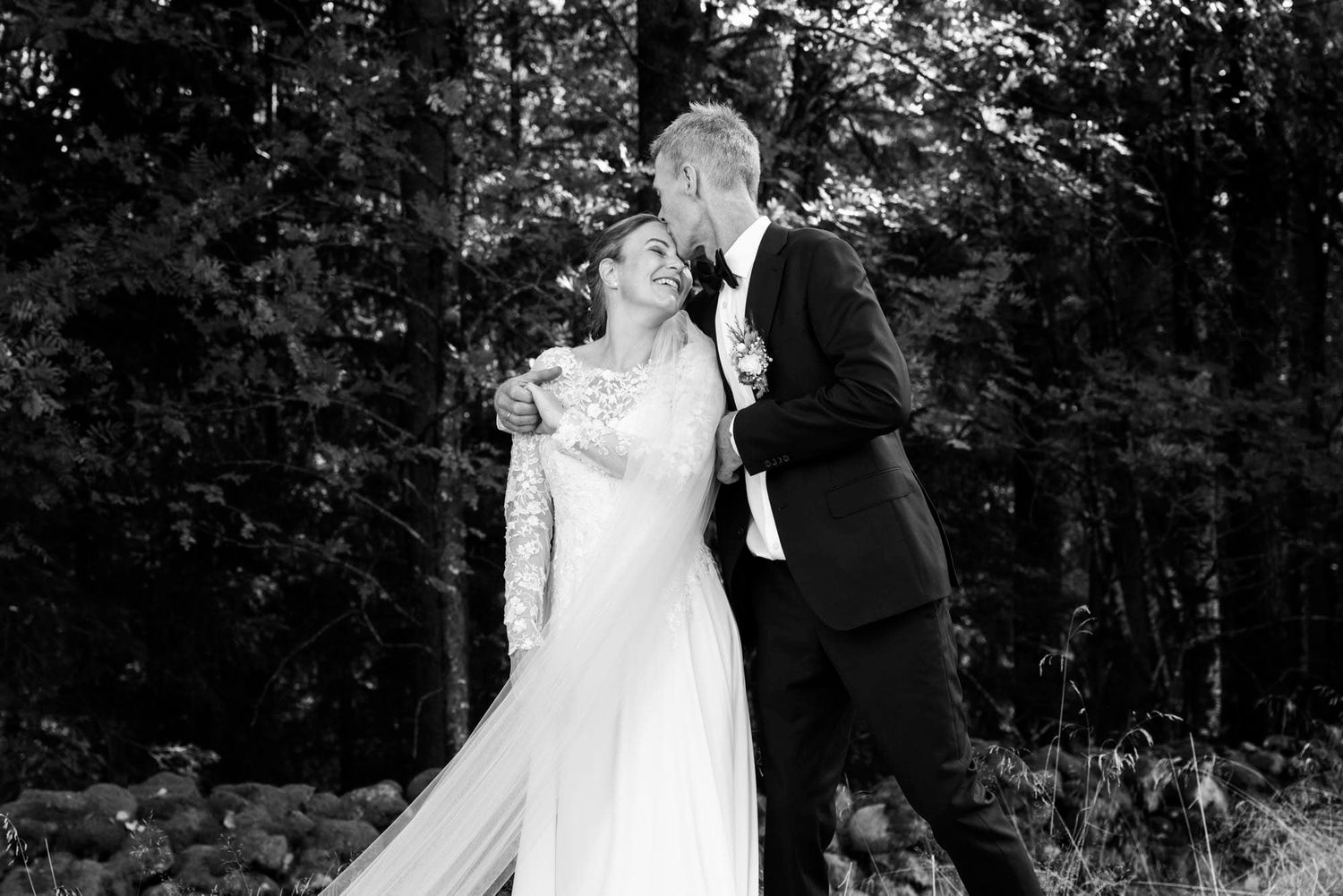 Brudgom som krysser brud på panna på fotografering i skogen i Lyngdal