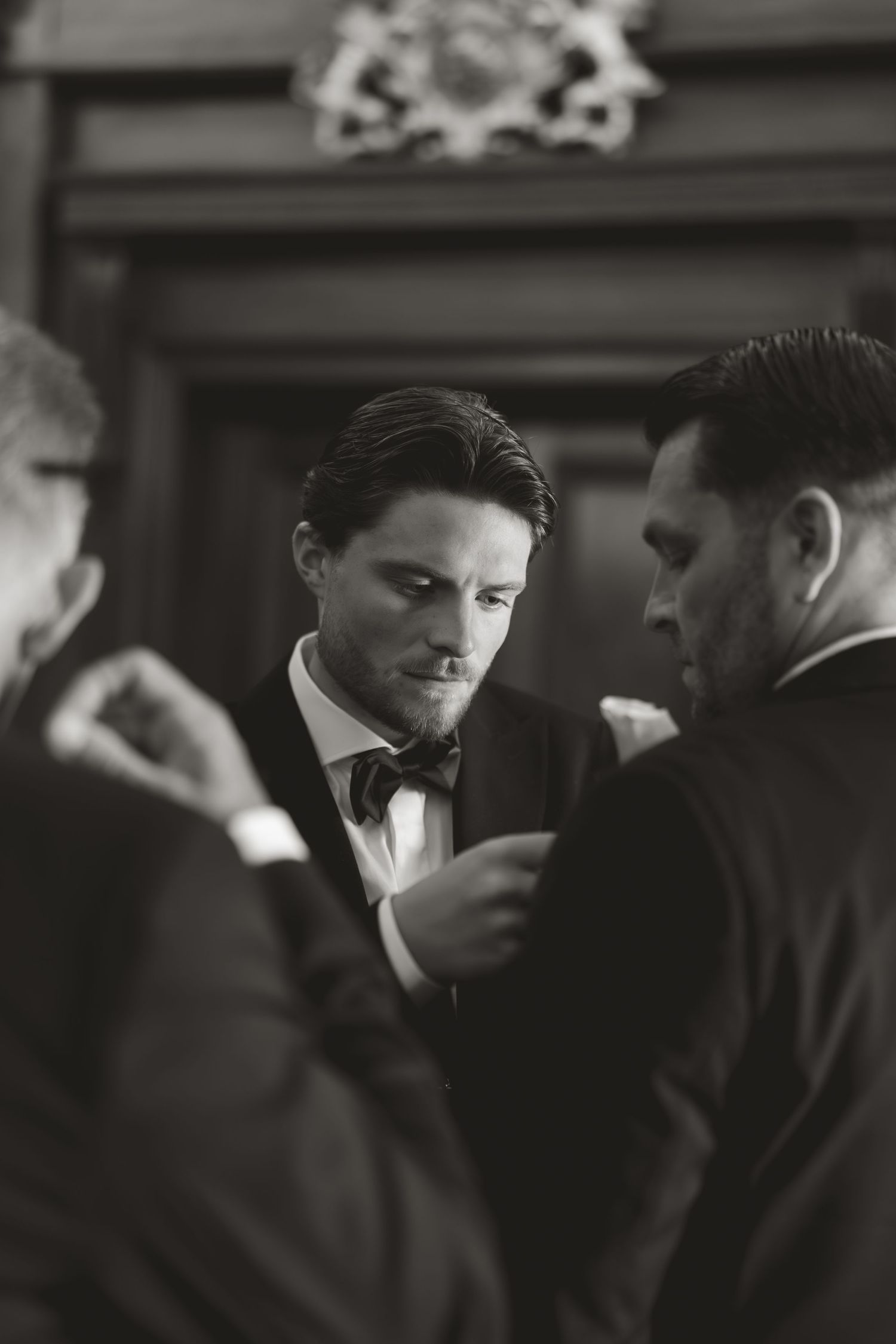 Formal event with guests in black attire engaged in conversation in elegant interior setting.
