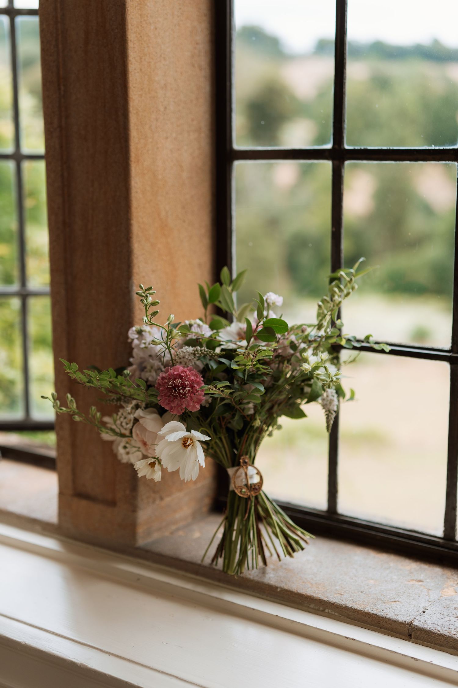 Beautiful pastel floral arrangement with delicate wildflowers sits along a sunlit window ledge.