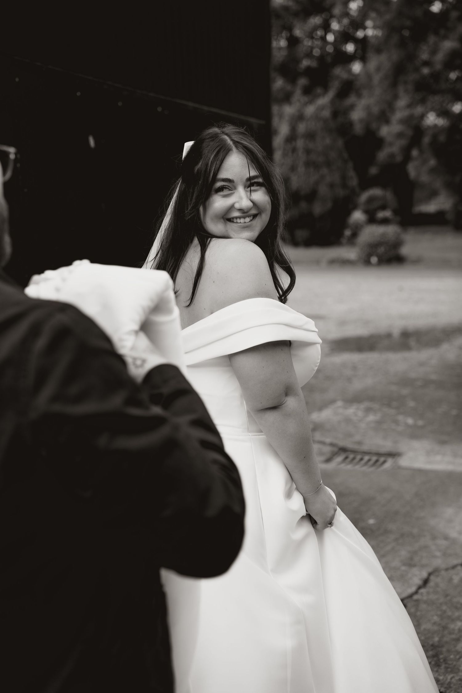 Candid black and white photo of wedding guests enjoying a celebration outdoors.