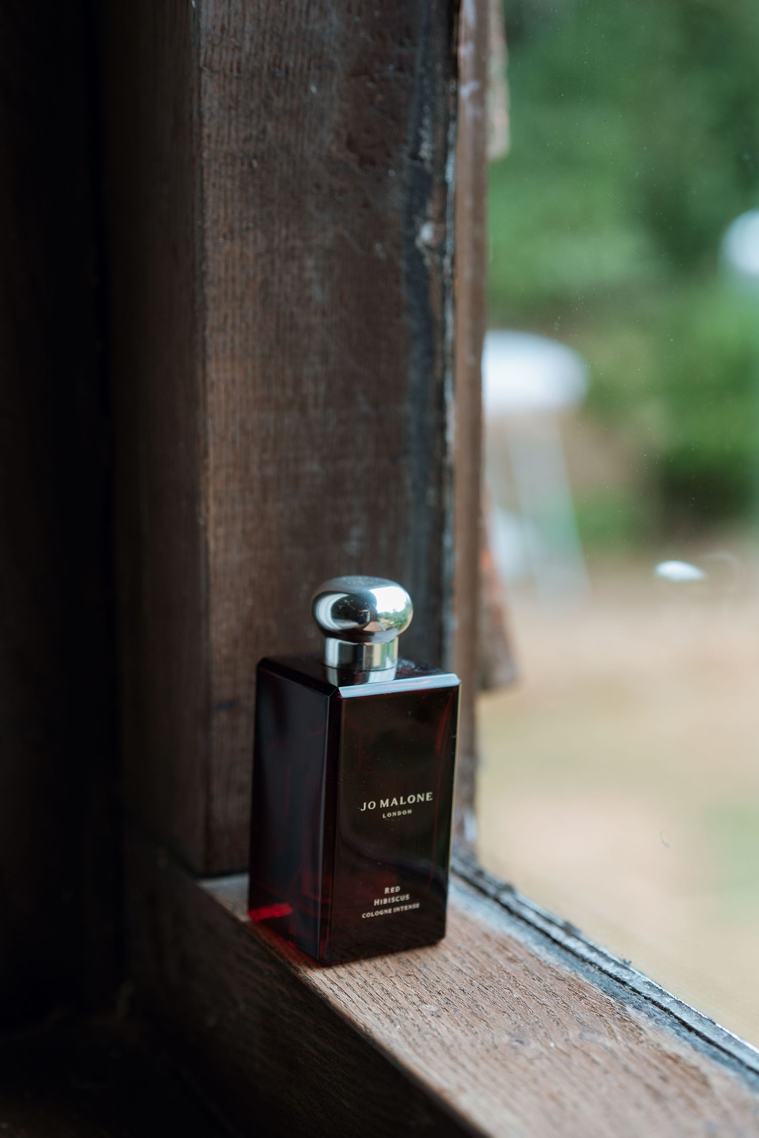 Close-up shots of a perfume bottle placed on a wooden windowsill.
