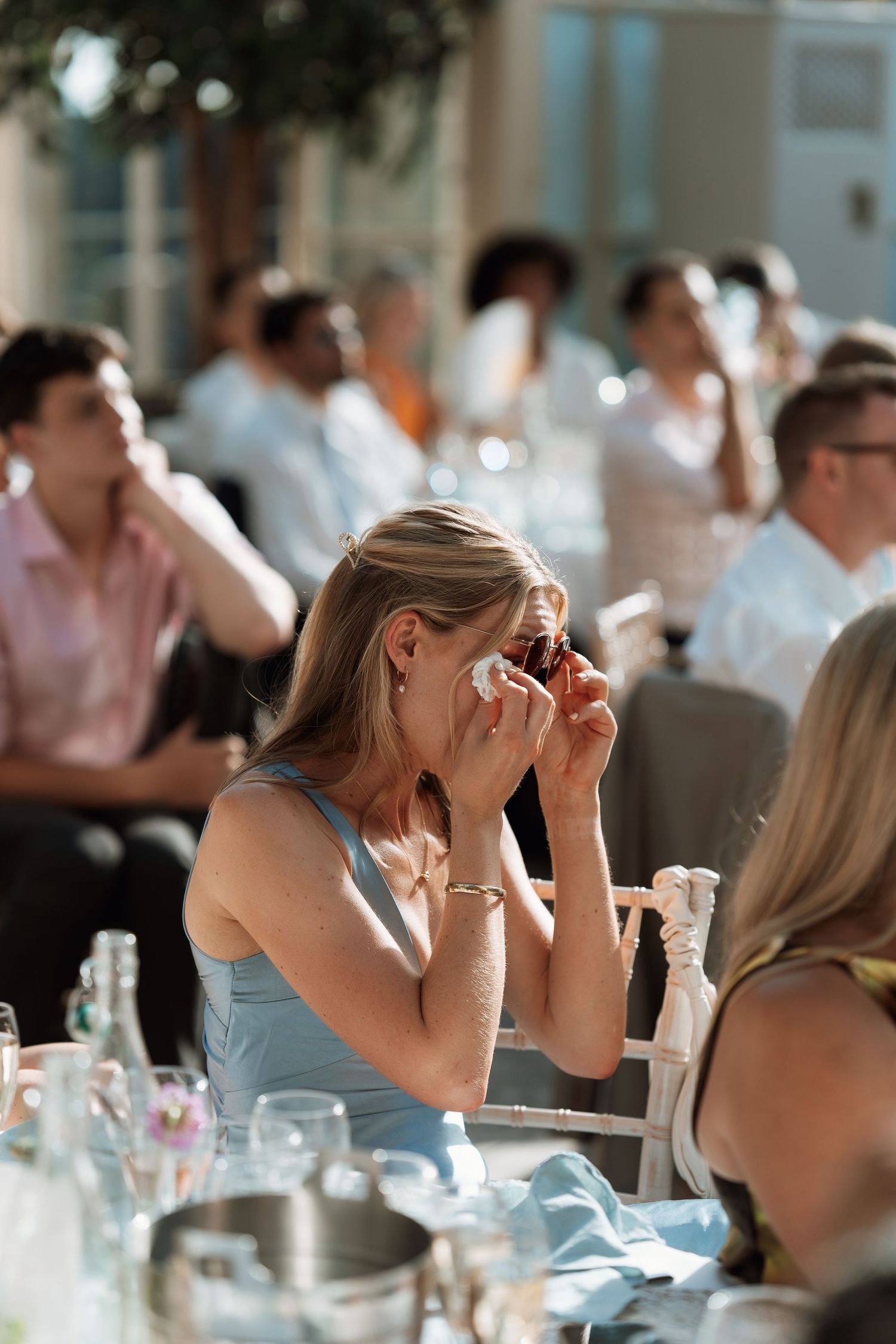 An emotional guest wipes tears during a wedding reception.