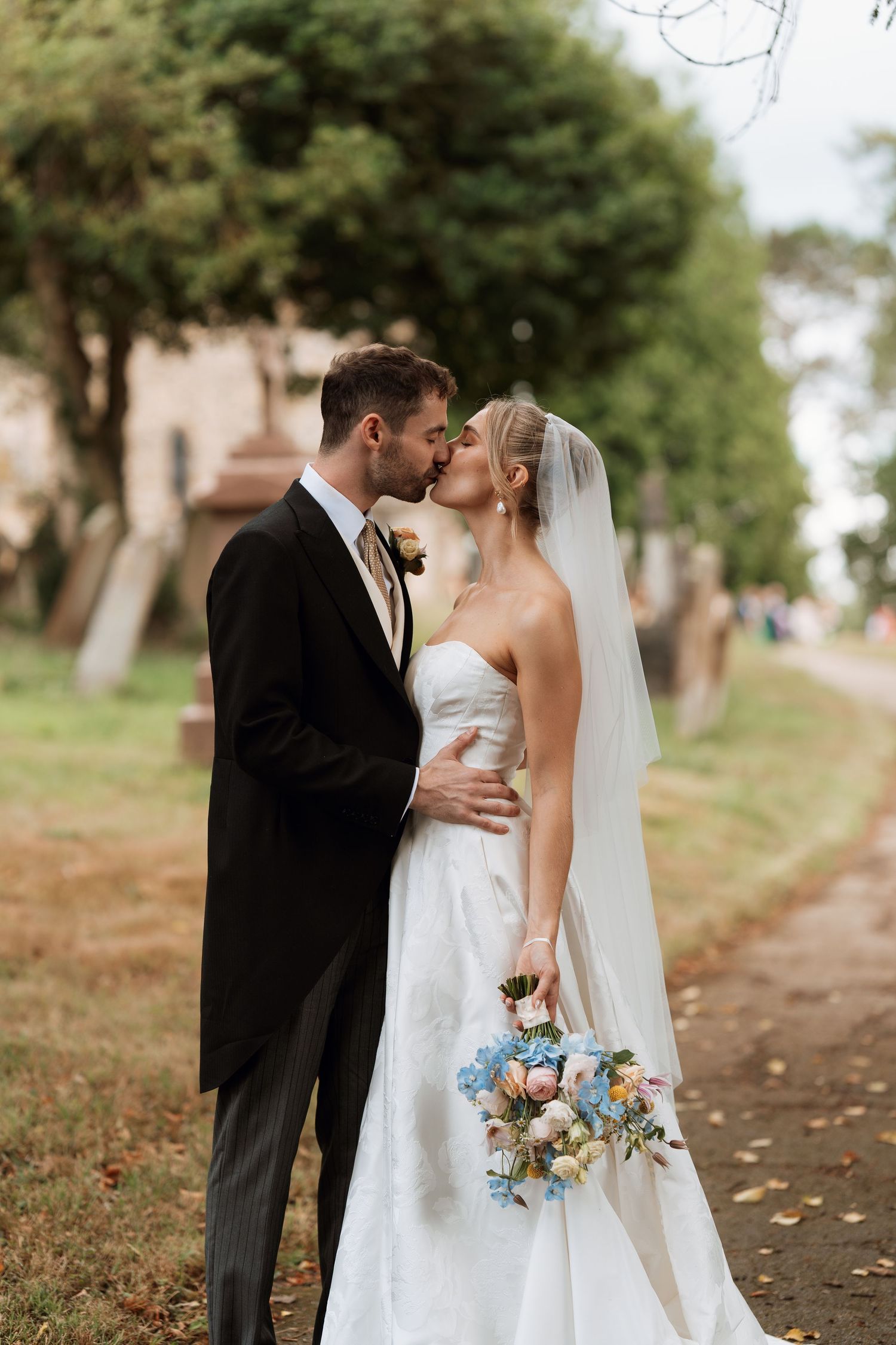 A romantic outdoor wedding portrait with a beautiful bouquet of blue and white flowers.