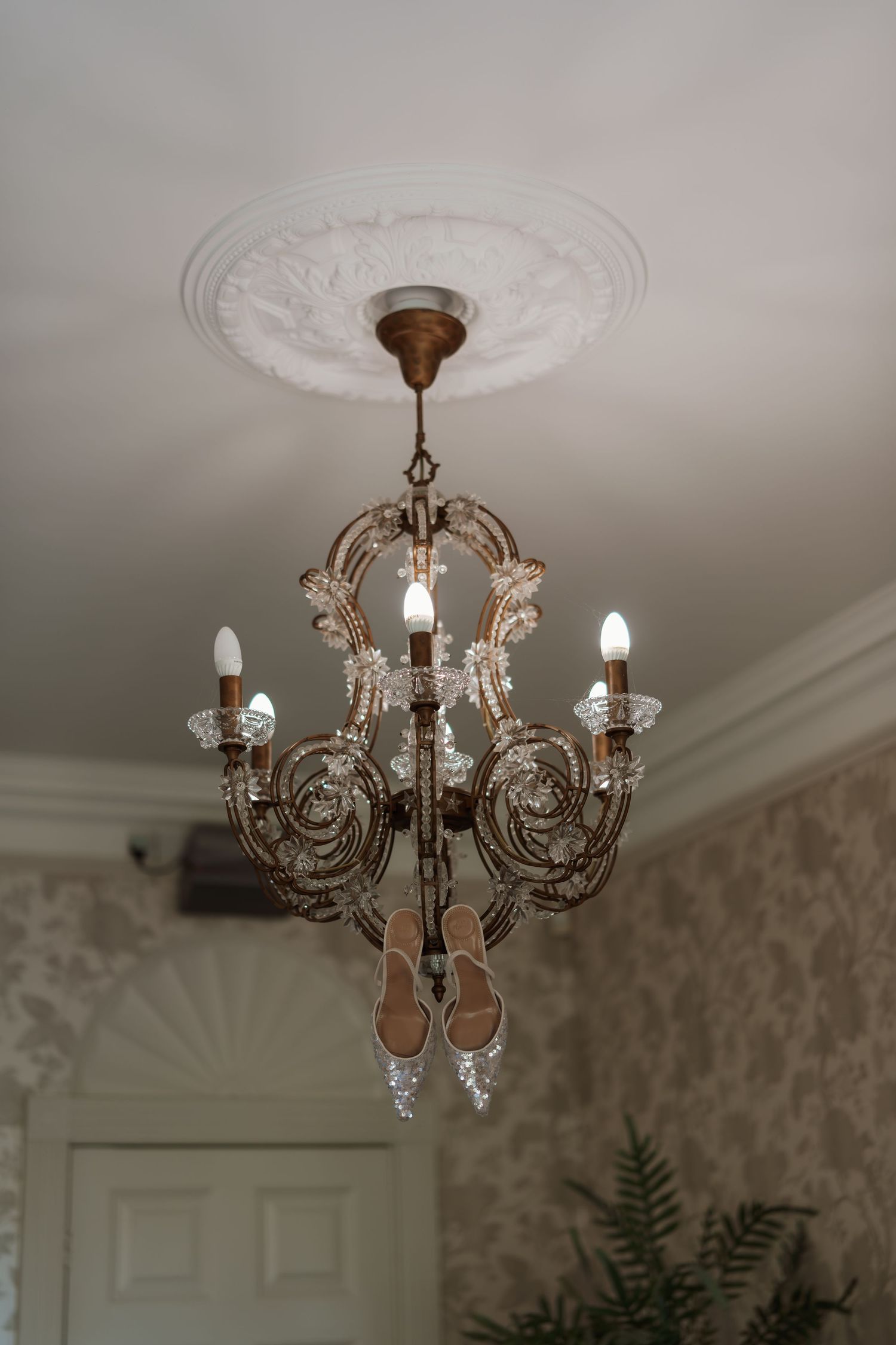 Elegant crystal chandelier with ornate details hanging from a white ceiling with decorative molding.
