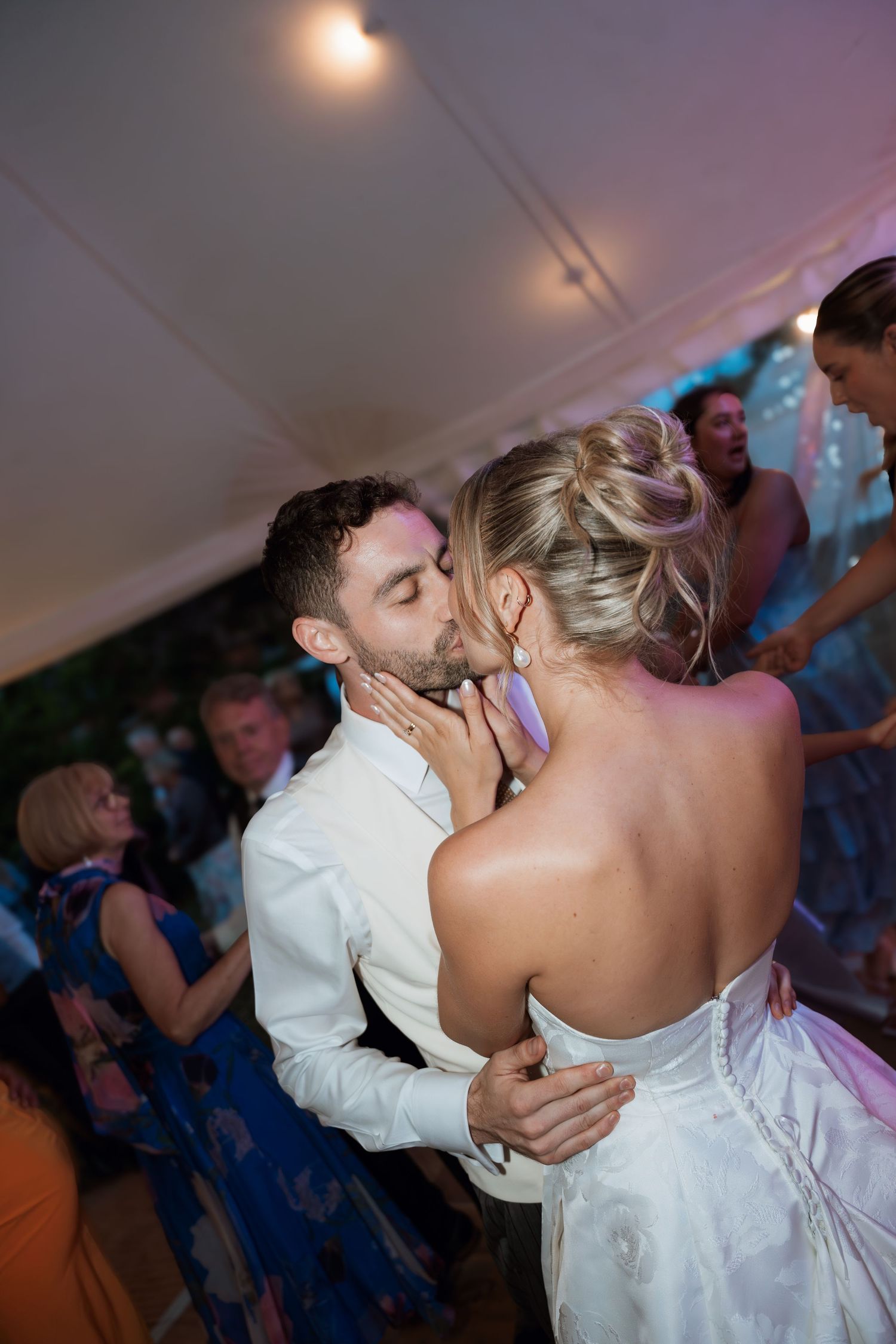 A couple shares an intimate dance moment under soft lighting at their wedding reception.