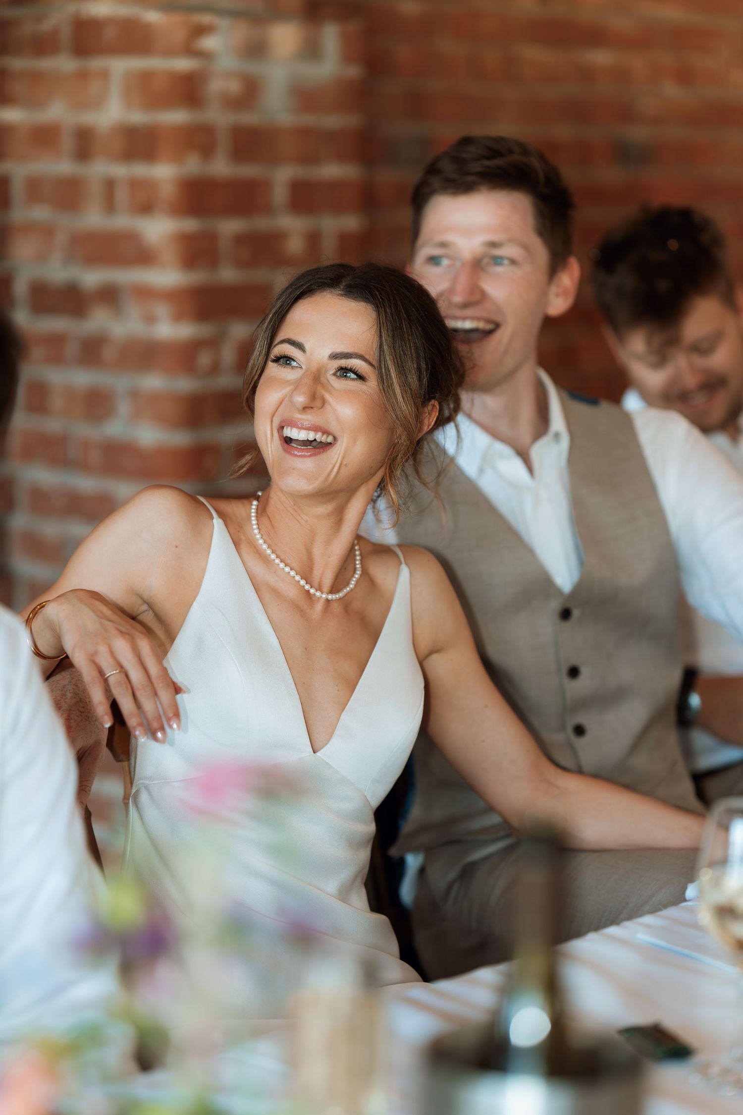 A joyful wedding reception scene with laughter and celebration at a rustic venue.