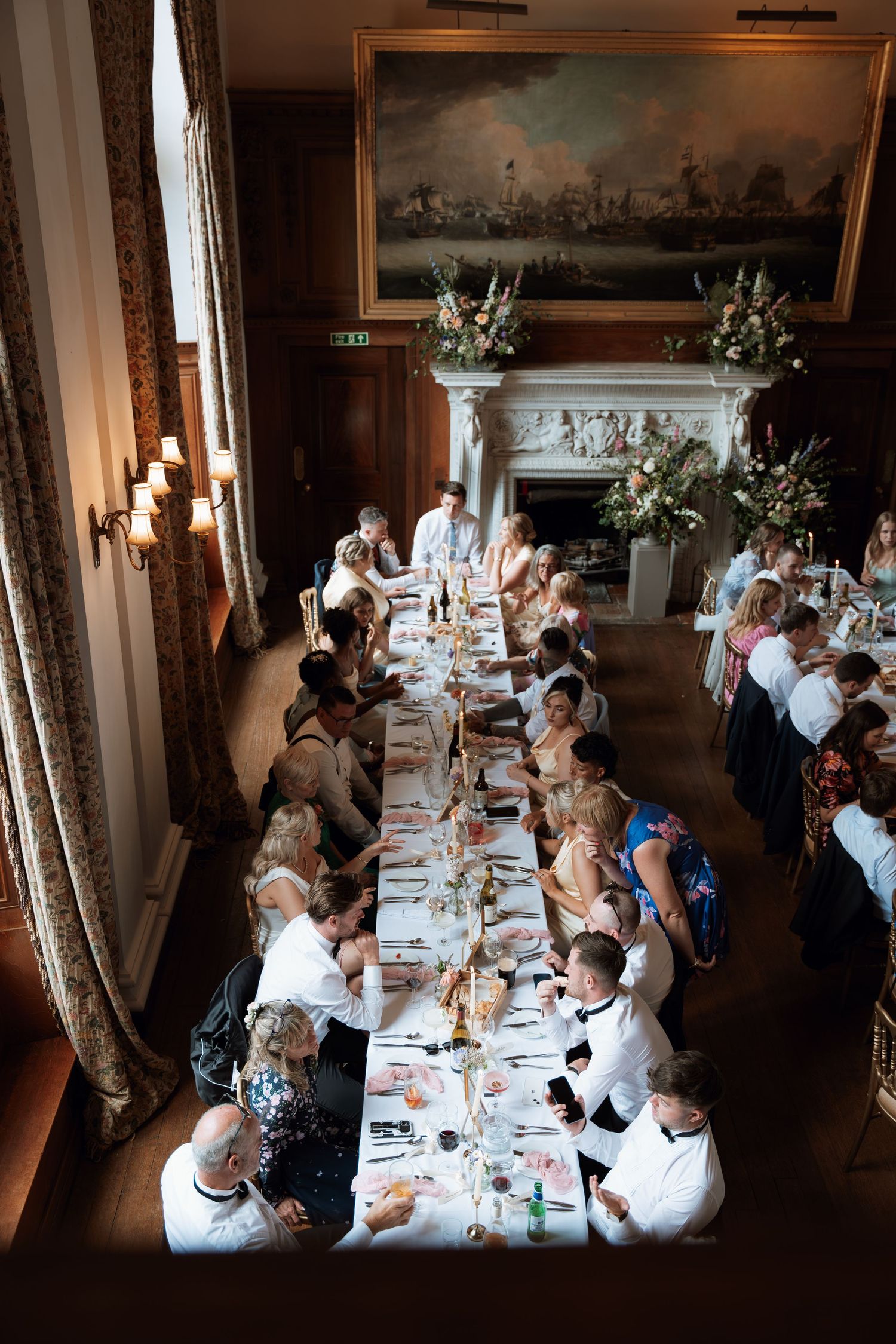 Elegant formal dining reception at a historic venue with guests seated at long tables adorned with floral centerpieces.