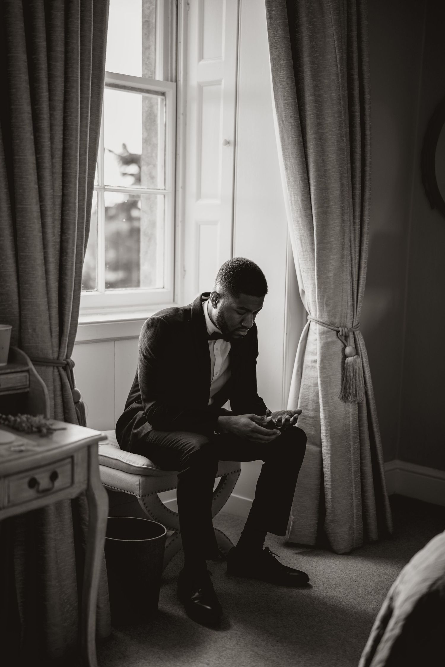 A contemplative moment captured in black and white by a window.