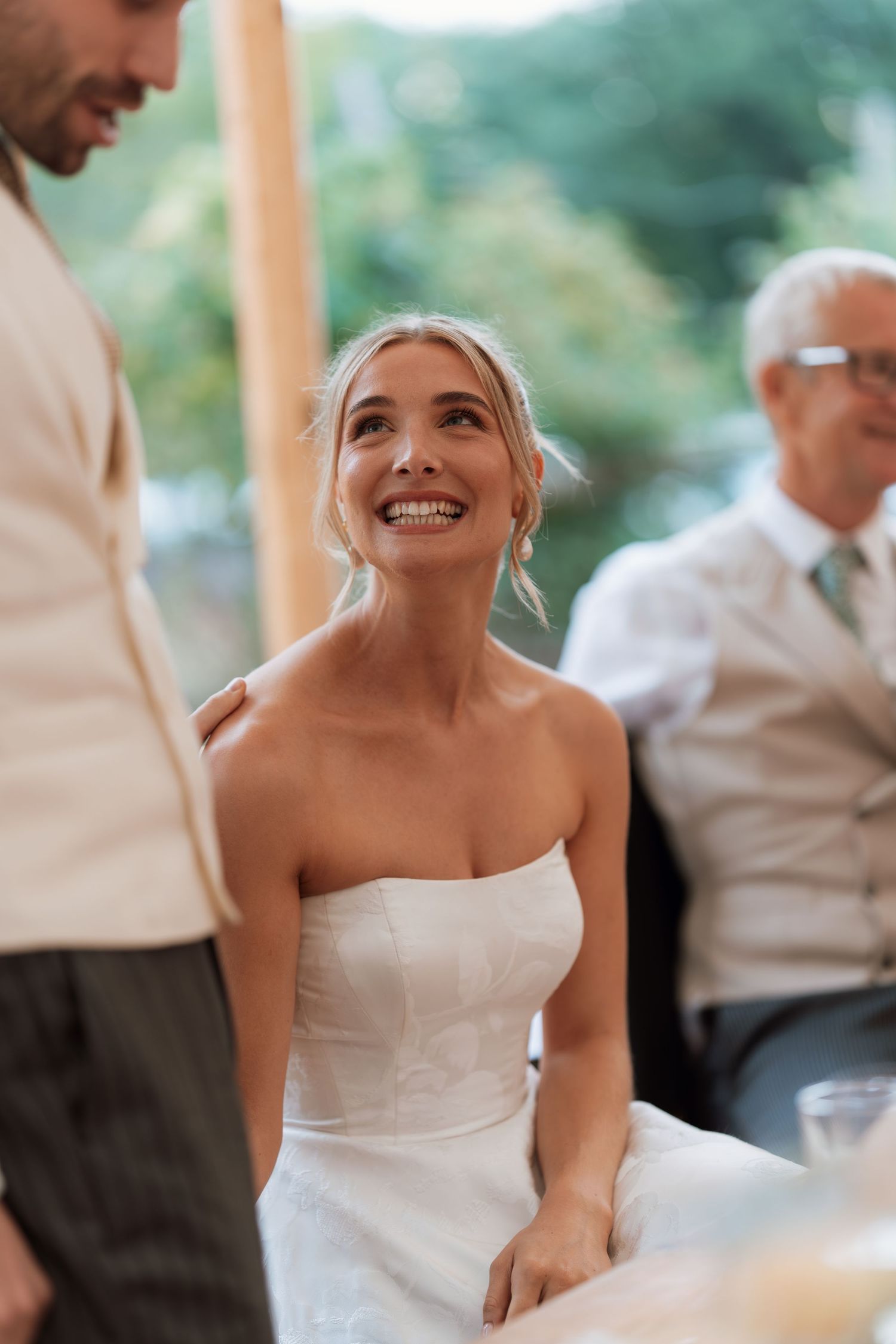 Candid moment of joyful bride smiling during wedding reception.