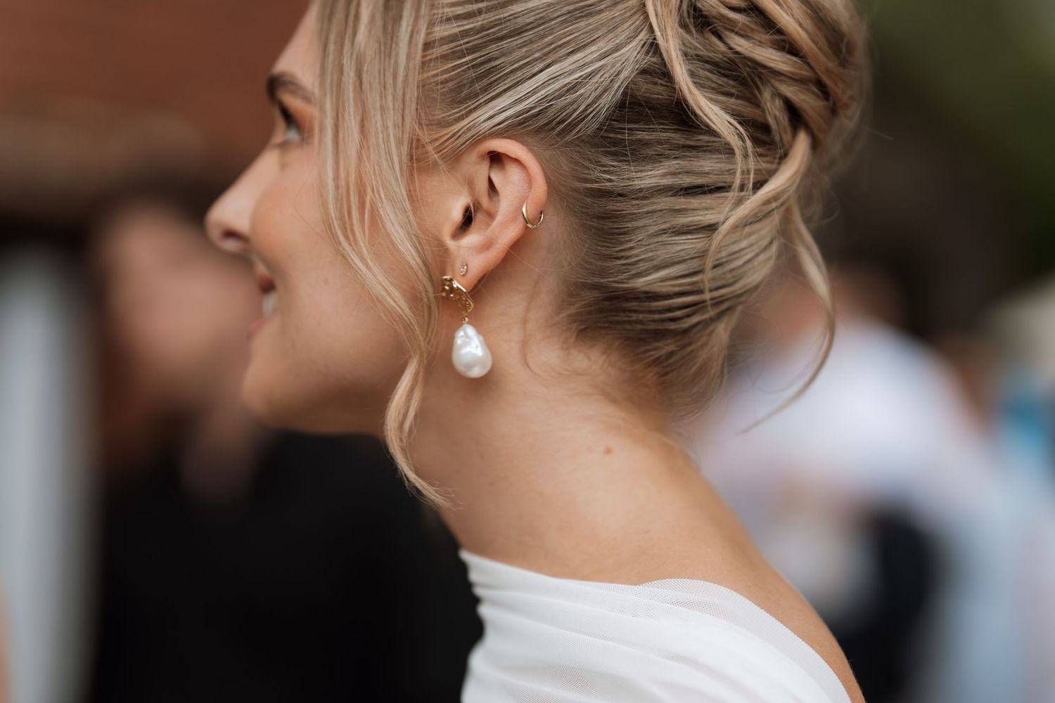 Side profile of wedding party members smiling and conversing during outdoor celebration.