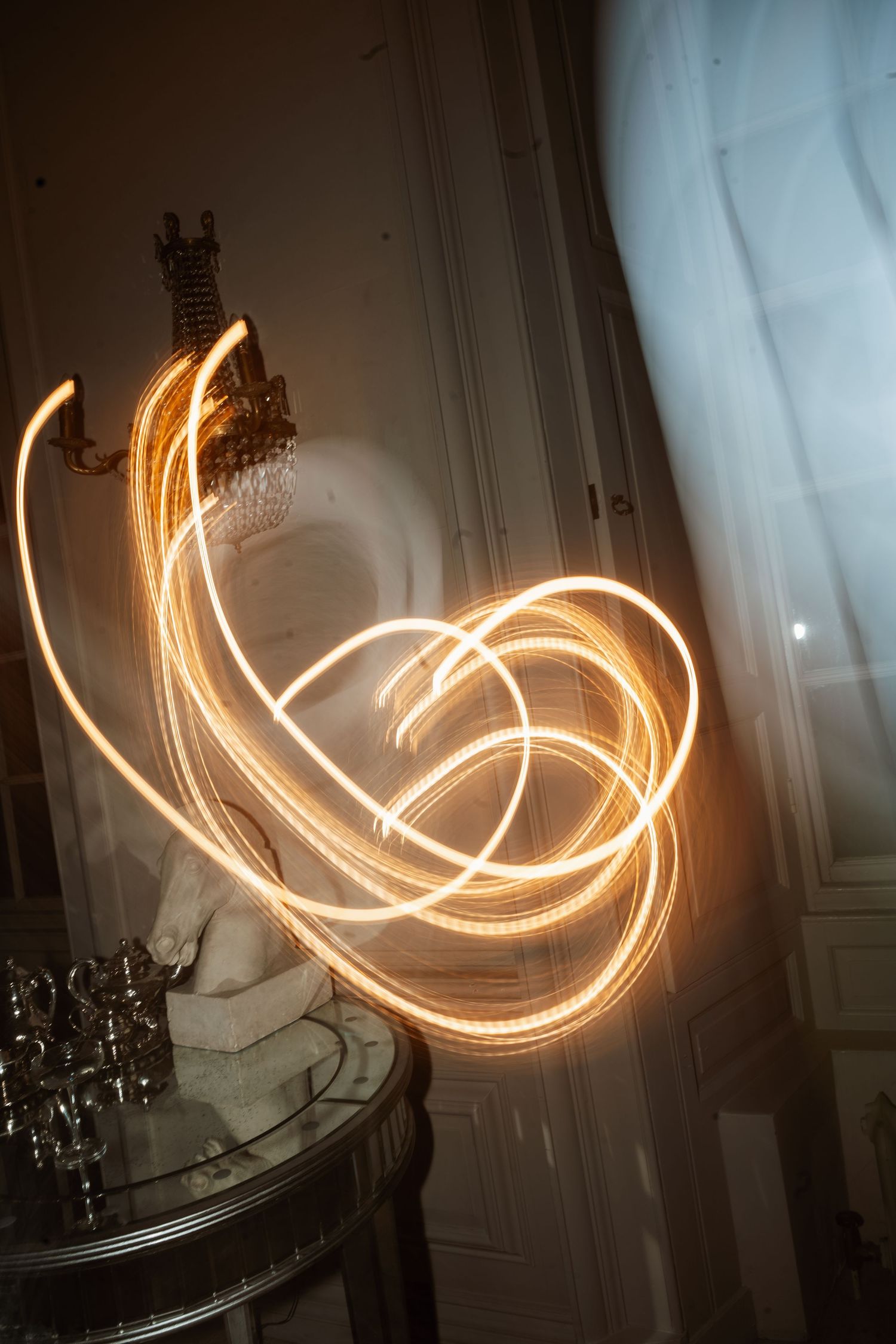 Long exposure light painting creates glowing swirls against a dark background.