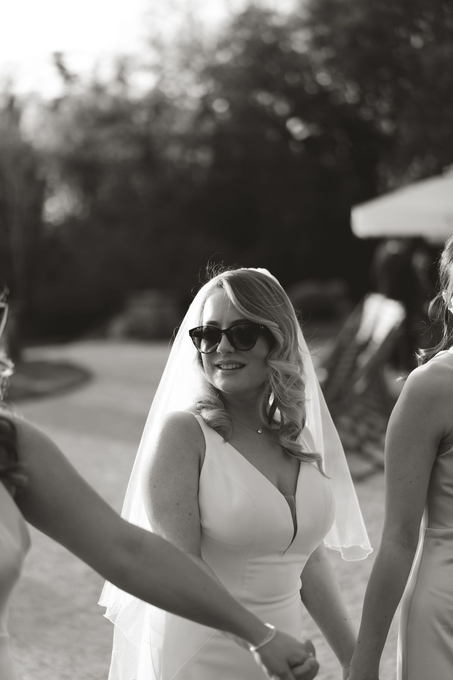 Black and white portrait of a bride wearing sunglasses and a flowing veil.