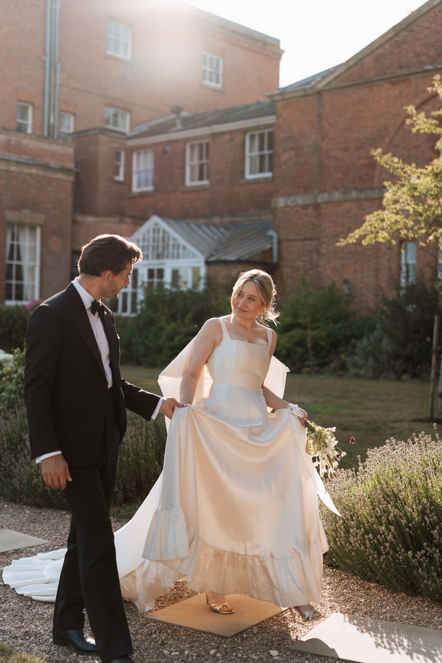 A couple shares a romantic moment in front of a historic brick building during their wedding photoshoot.