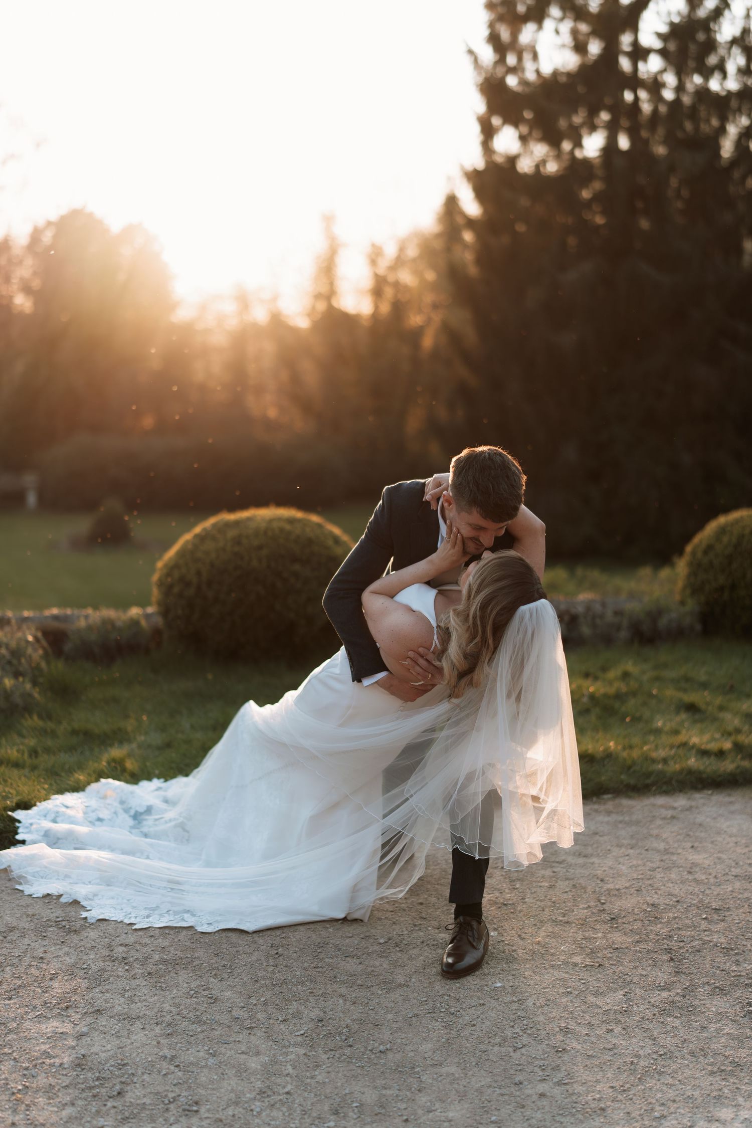 Romantic sunset wedding photos of couple embracing on a gravel path.