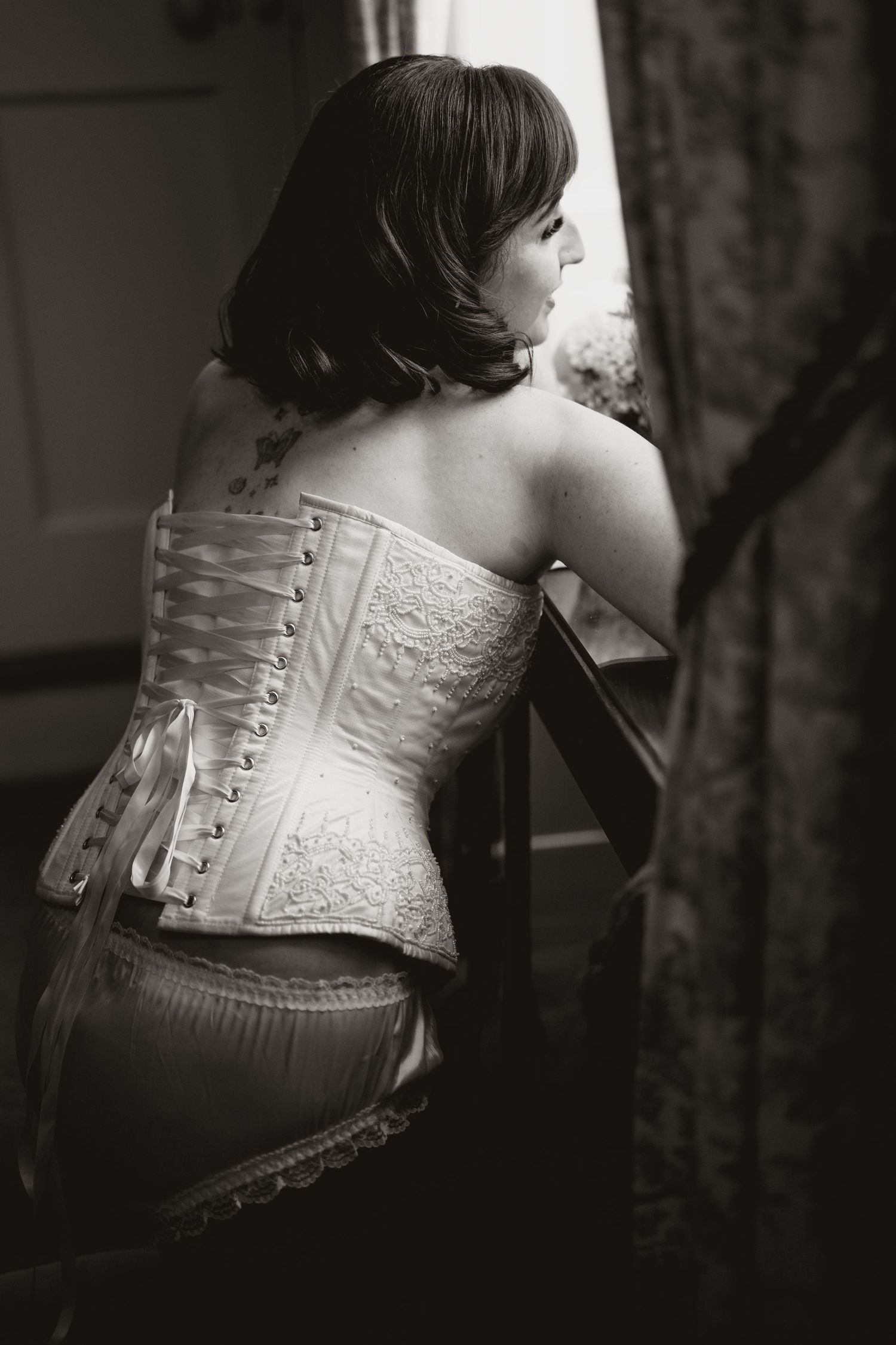 Black and white photo showing back detail of corset with intricate lace pattern.