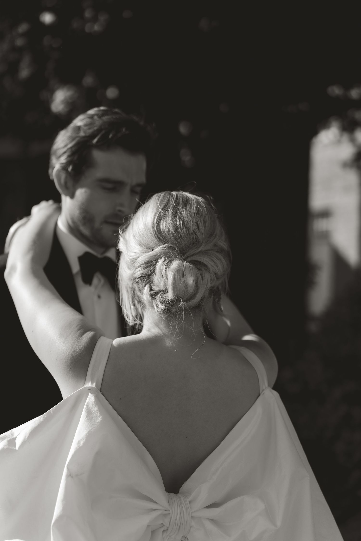 Black and white portrait of a couple in formal wear sharing an intimate dance moment.