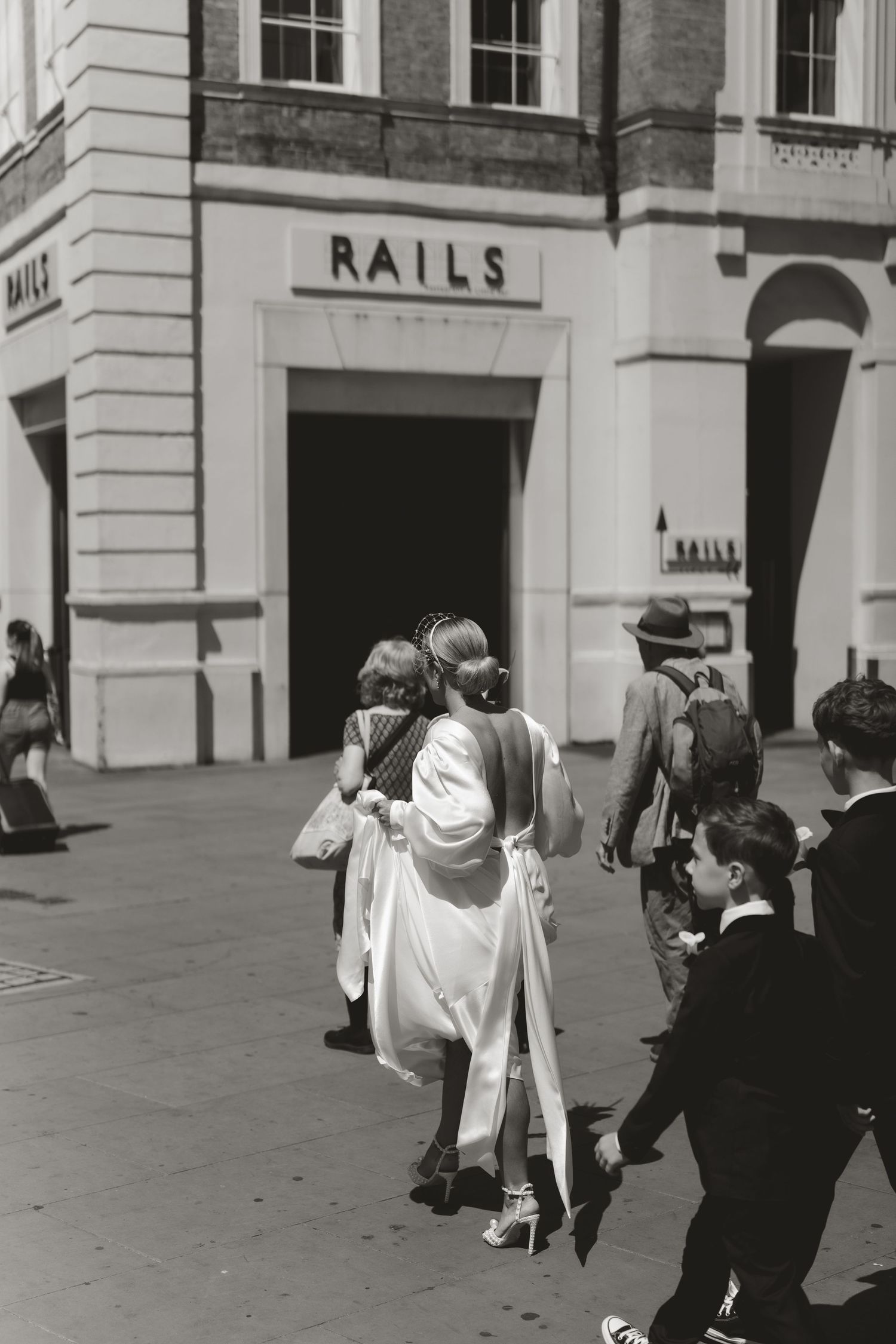 Group walking outside classical building facade with white stone architecture.