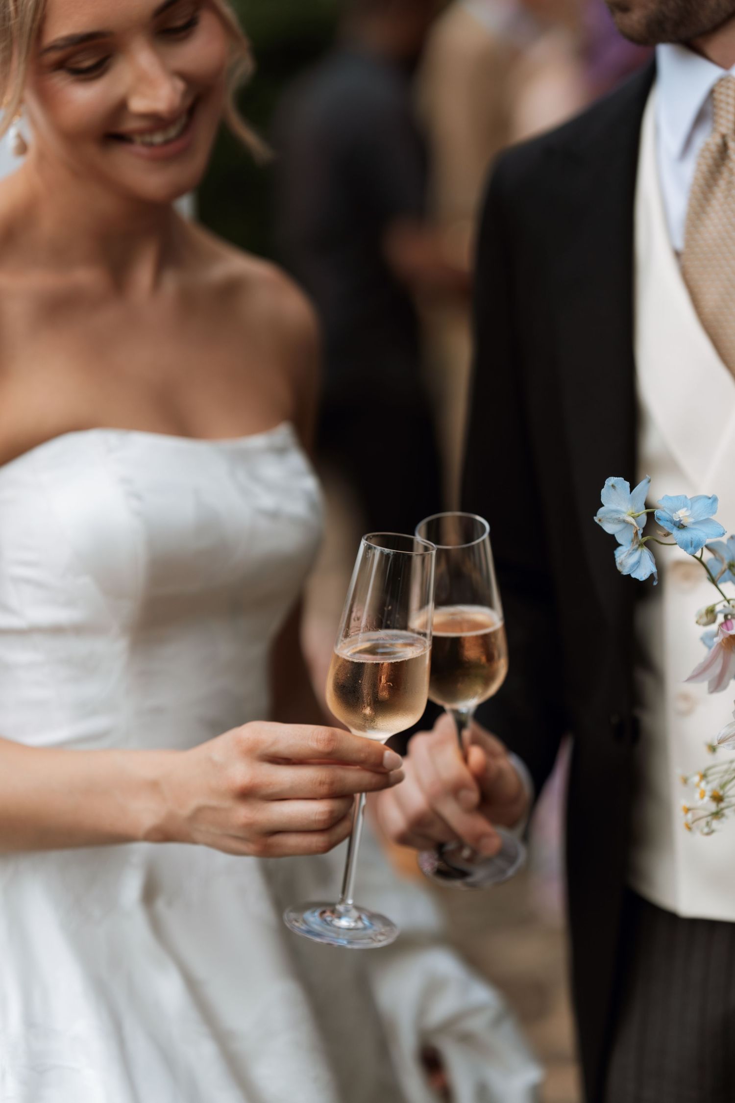 A romantic champagne toast moment with glasses of sparkling wine and delicate blue flowers.