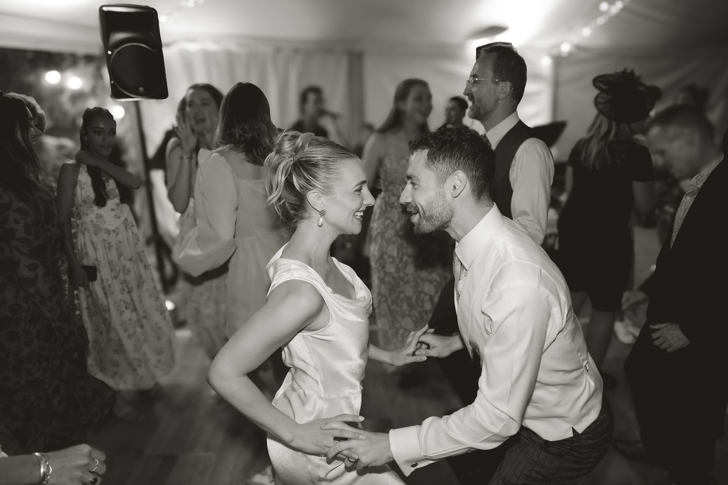 A black and white photo capturing energetic dancing at a lively wedding reception.