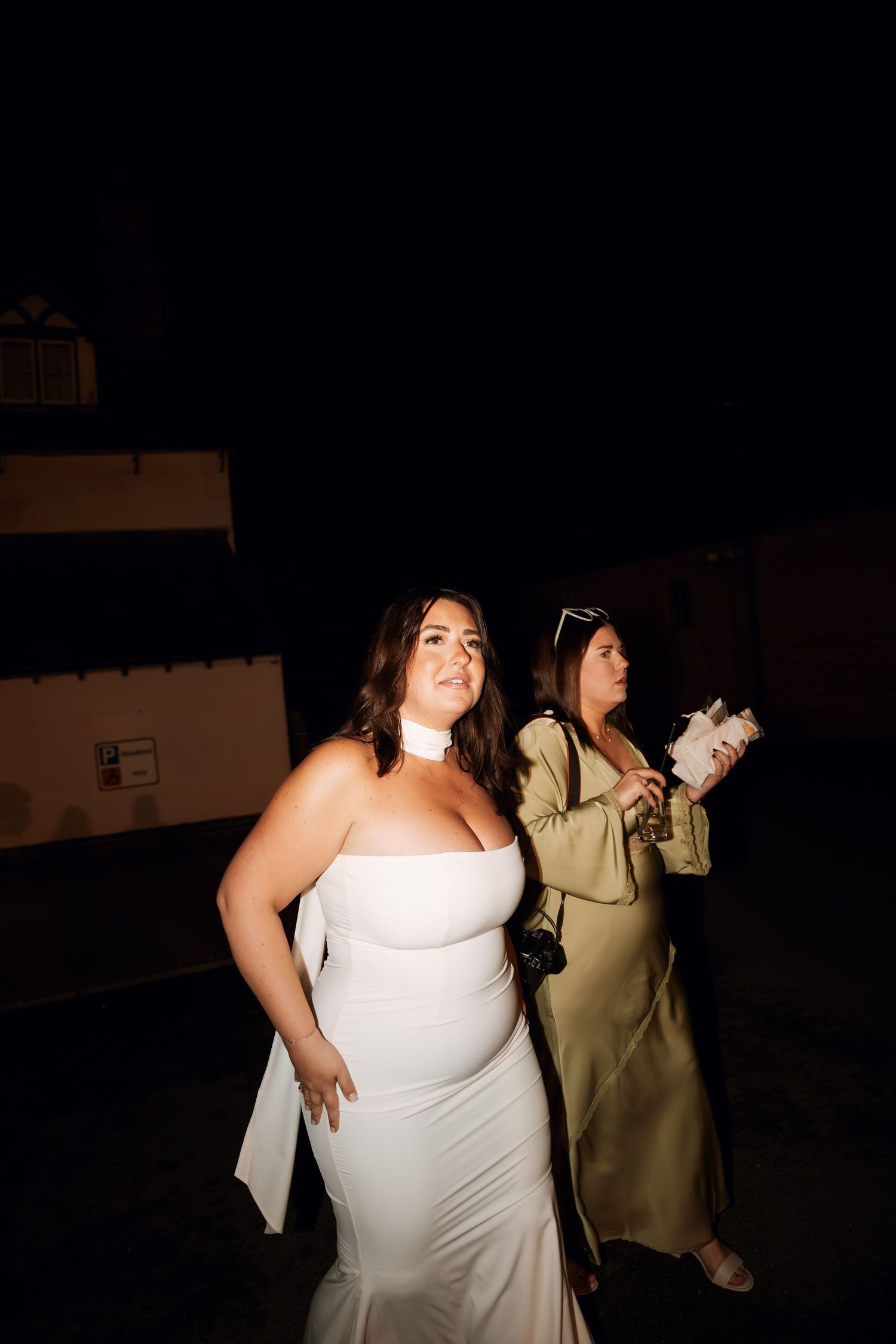 A bride in a white dress dances outdoors during a nighttime wedding celebration.