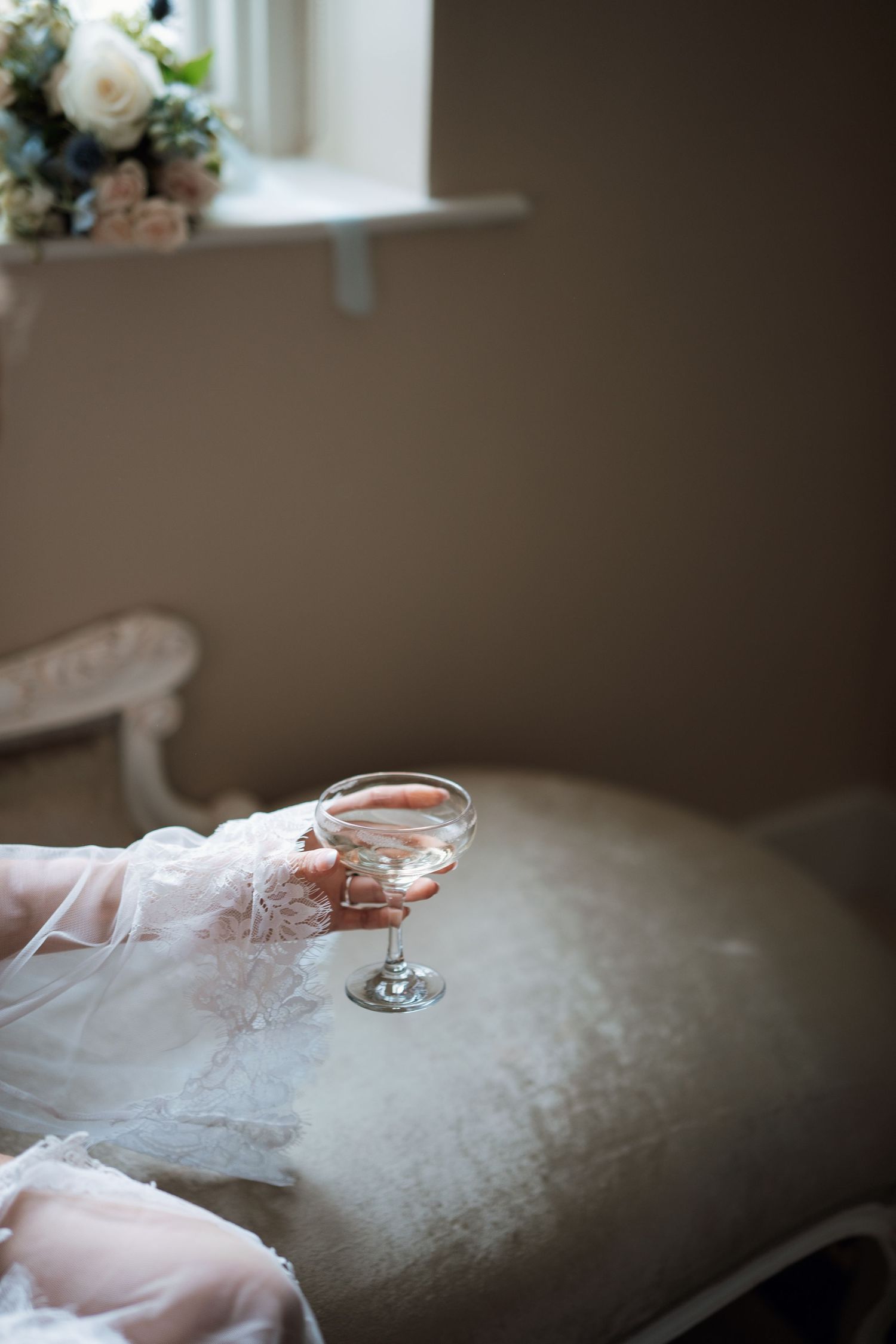Wedding detail shot of champagne glass and veil in soft natural light.