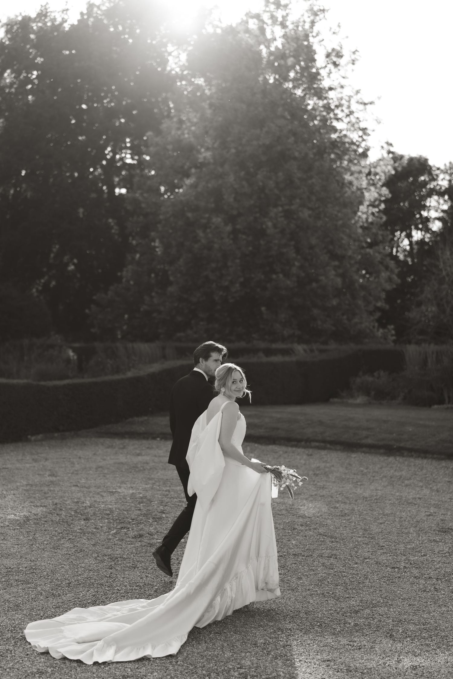 Silhouetted couple dancing on a grassy lawn during golden hour wedding photography.