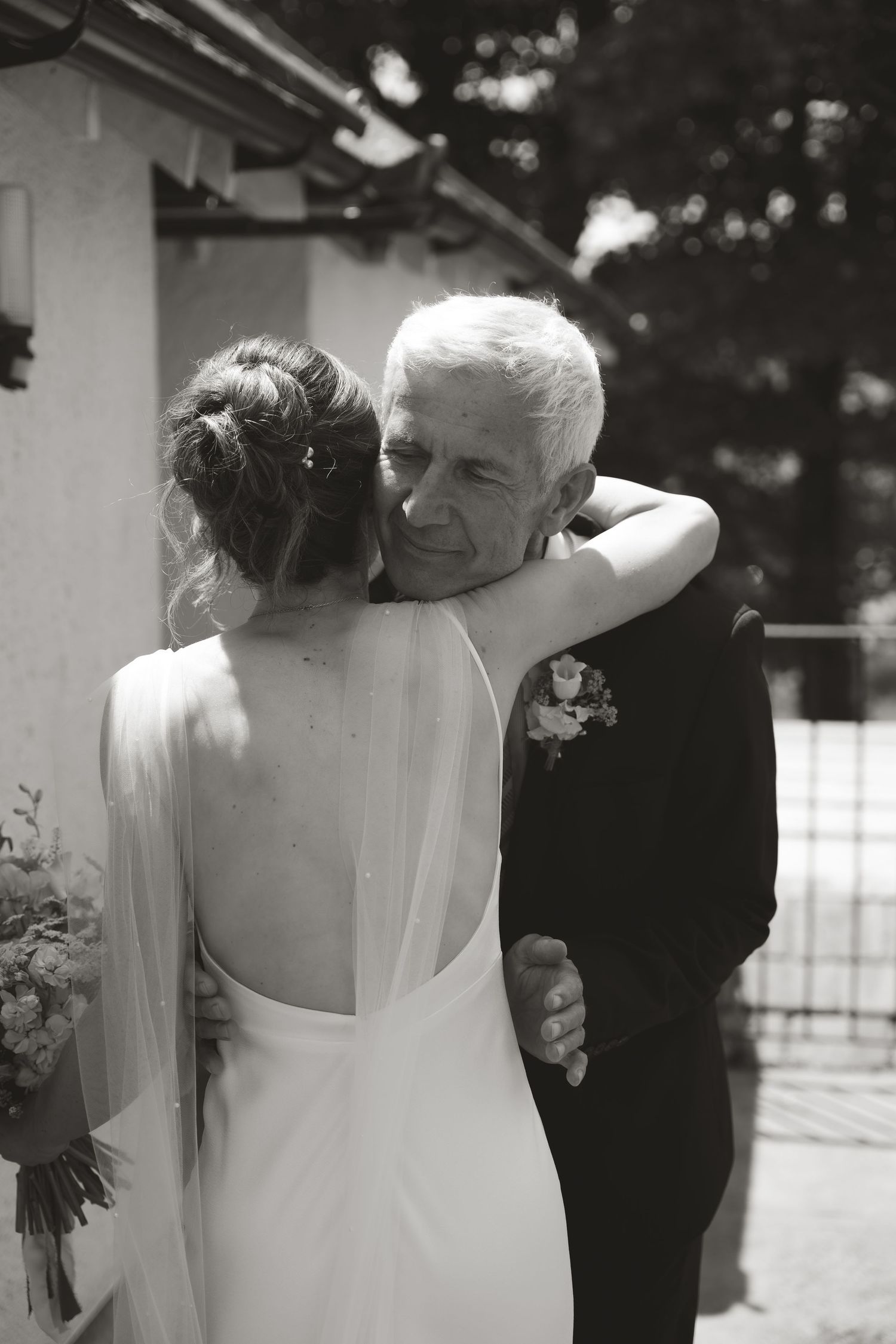 An emotional black and white wedding moment showing a tender embrace between a bride and her father.