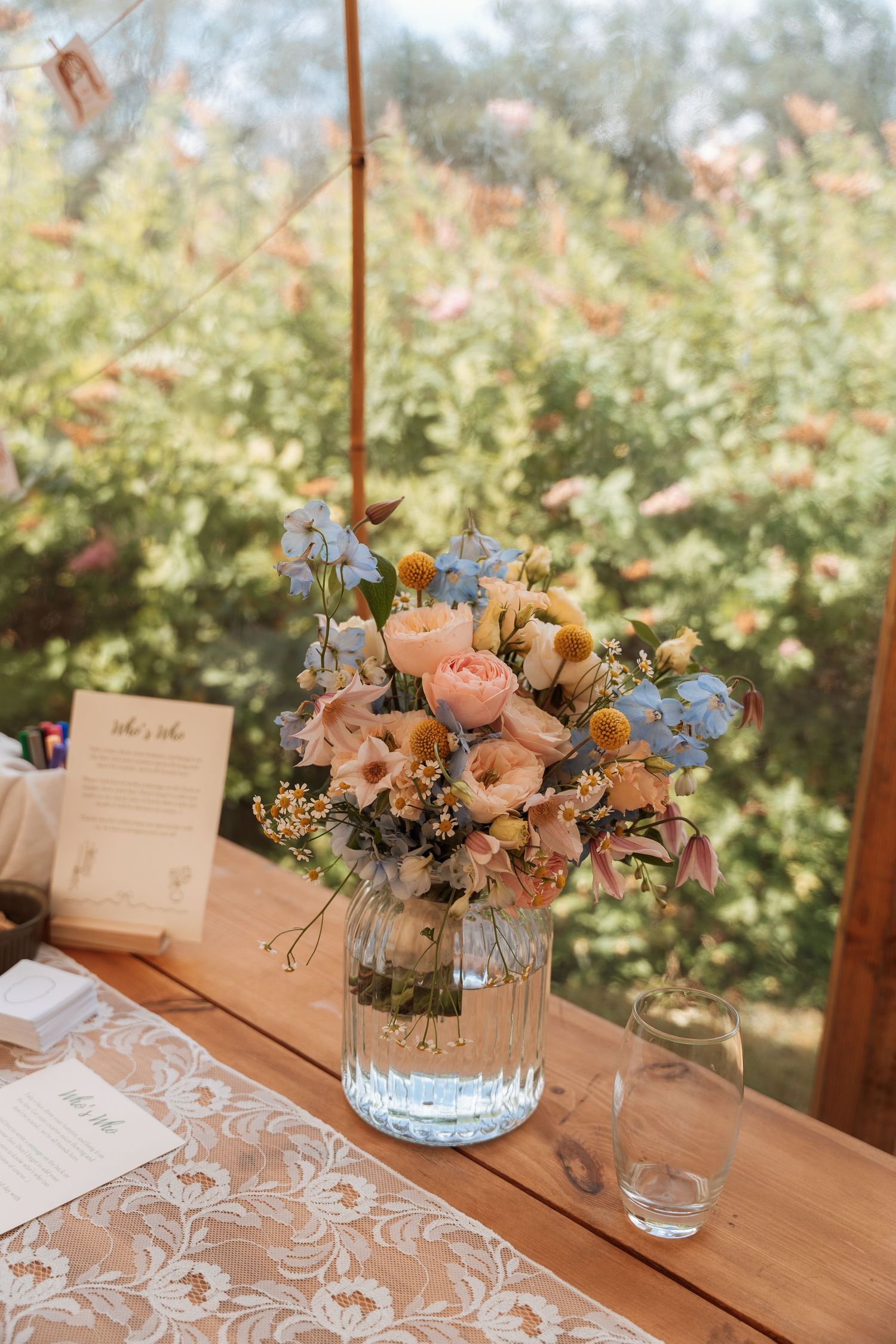 Elegant floral centerpieces with pink and blue flowers on a wooden table with place cards.