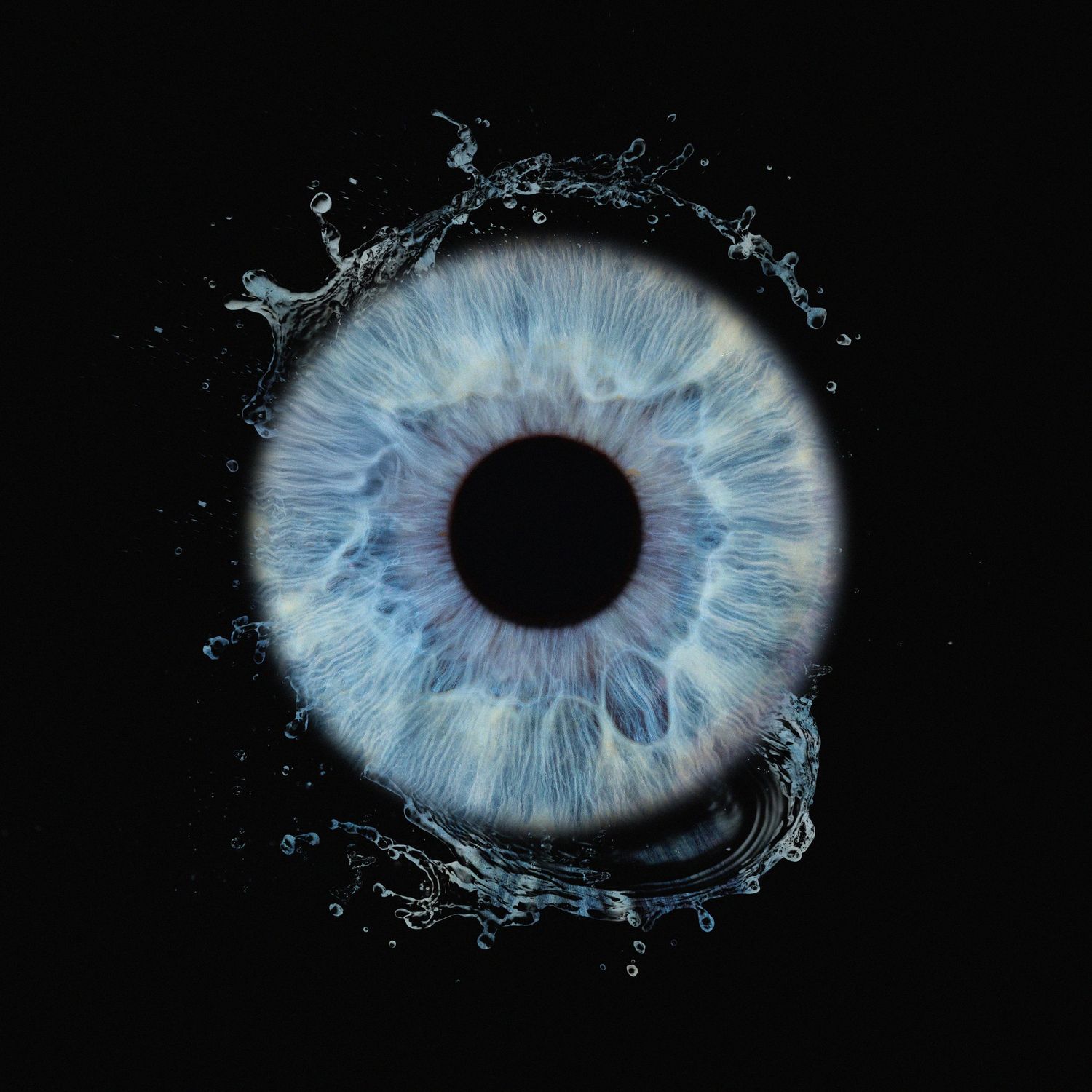 Artistic macro photograph of a light blue human iris with water splash effect on black background.