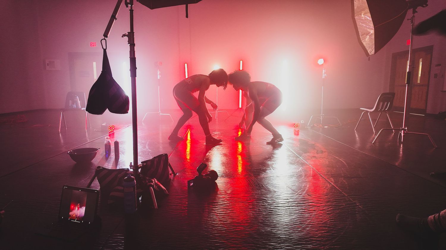 Silhouetted figures in atmospheric red-lit studio during professional photo shoot.