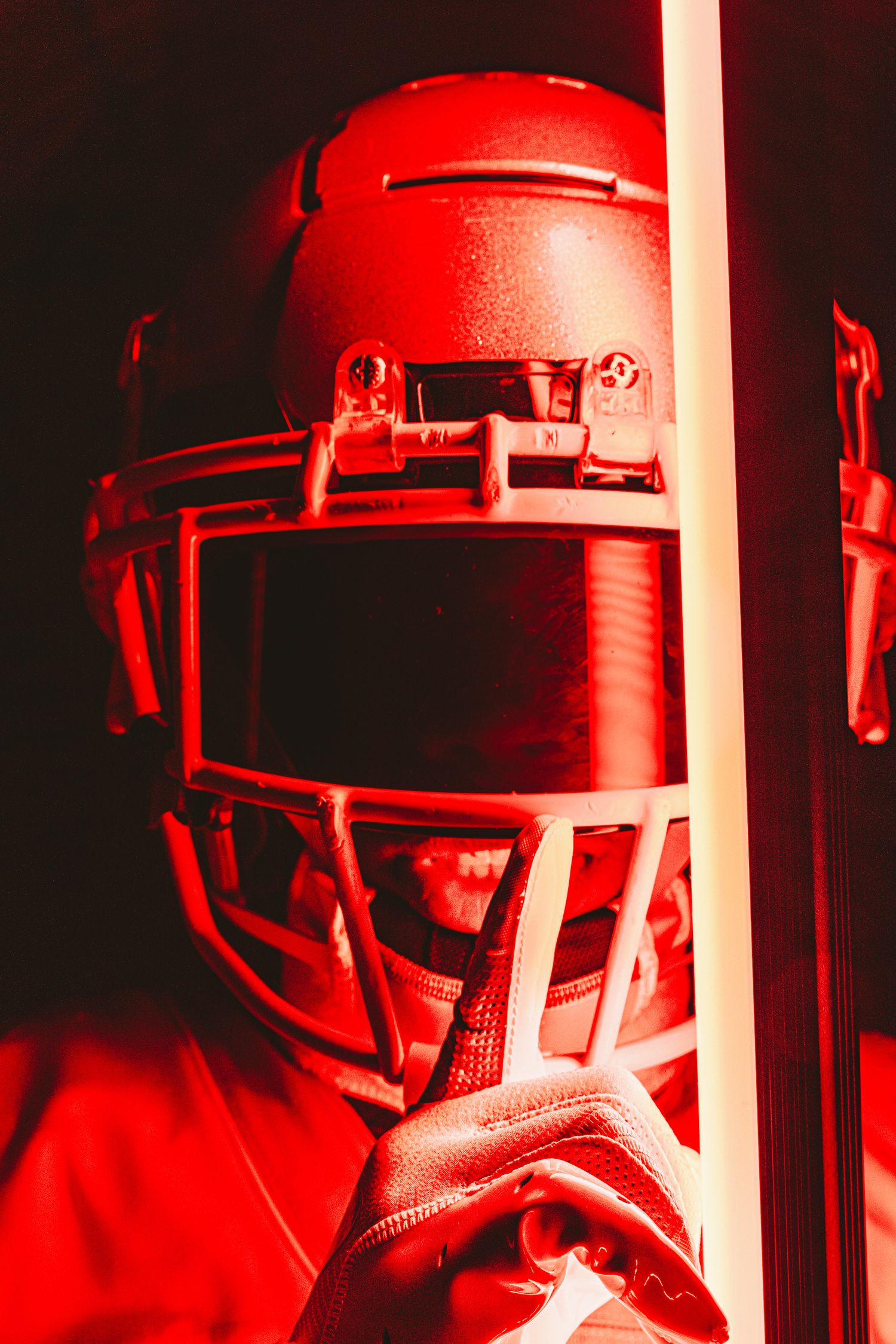 Football helmet detail shot with red lighting and glowing light bar effect.