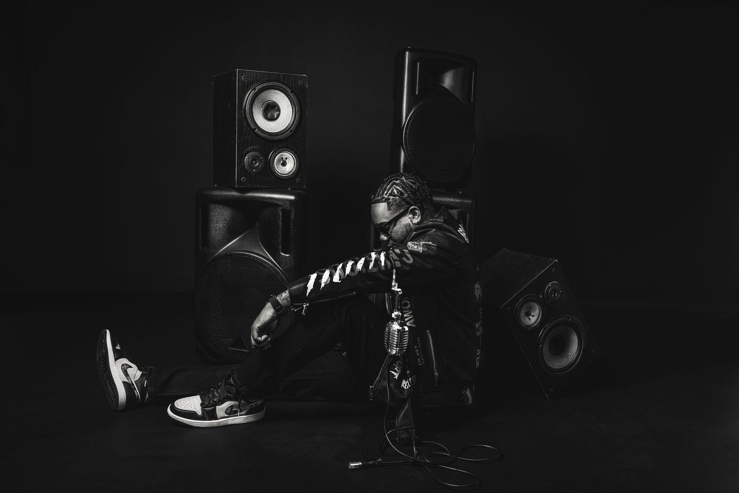 Dramatic low-key portrait of artist sitting among professional audio equipment.