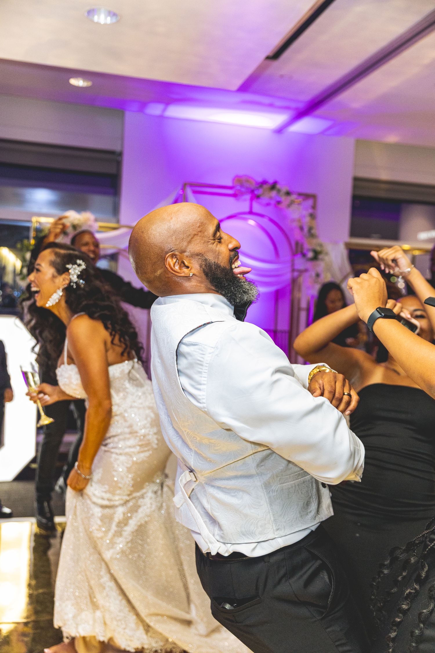 Lively dance party scene at an event with guests dancing energetically under purple lighting.