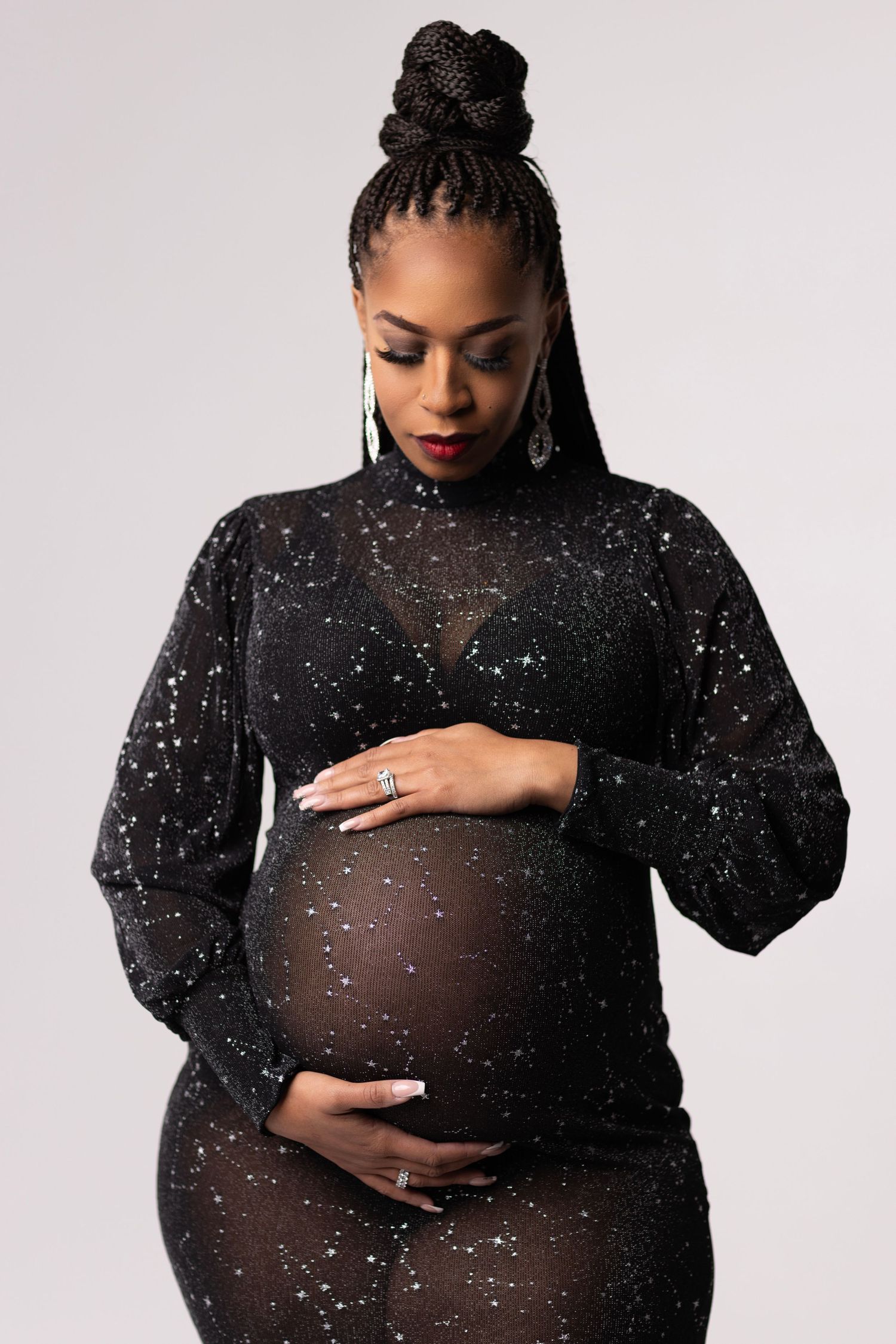 Maternity portrait in sheer sparkly black dress showcasing pregnancy silhouette.