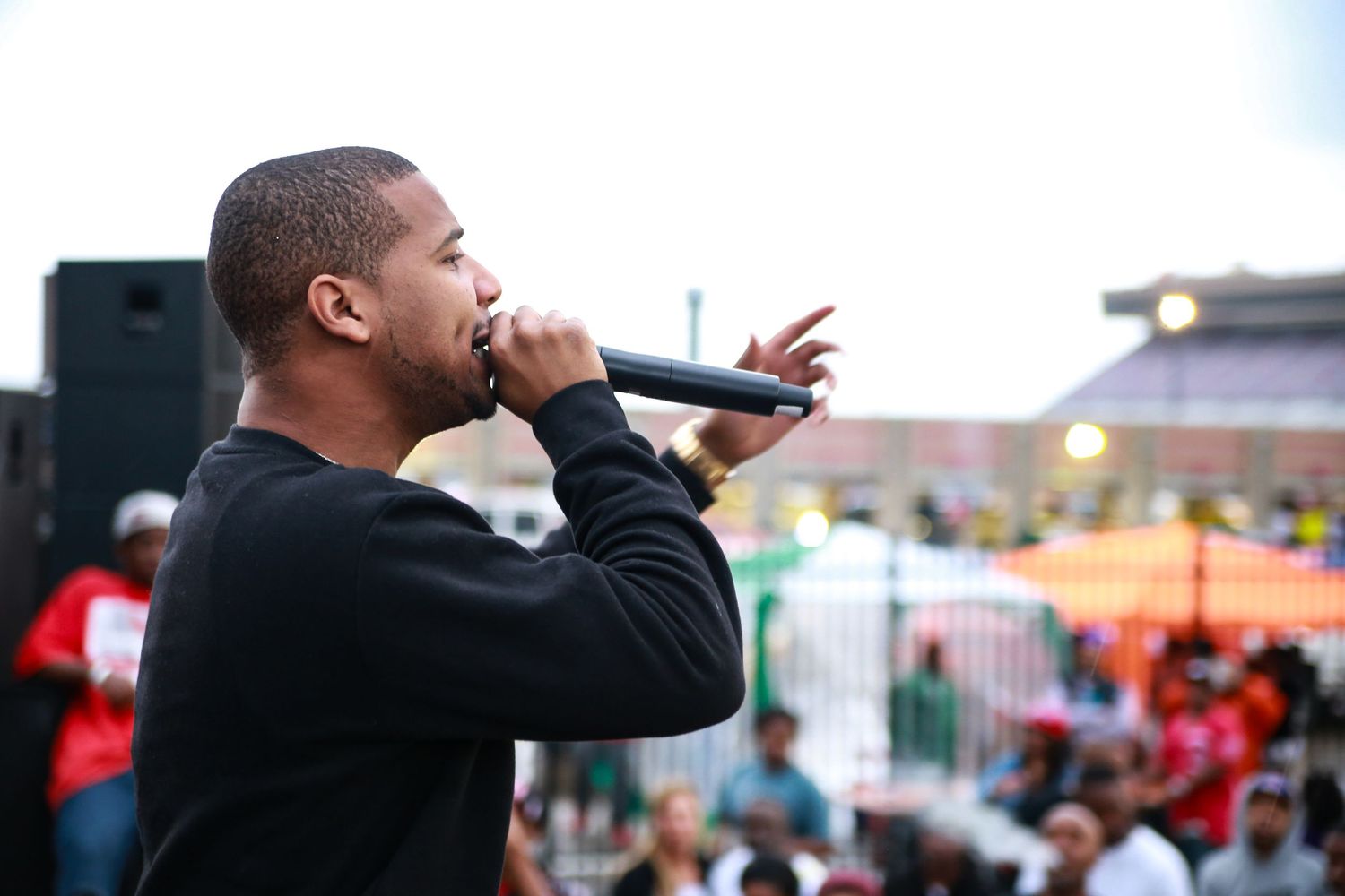 Juelz Santana performing with microphone at outdoor event venue.