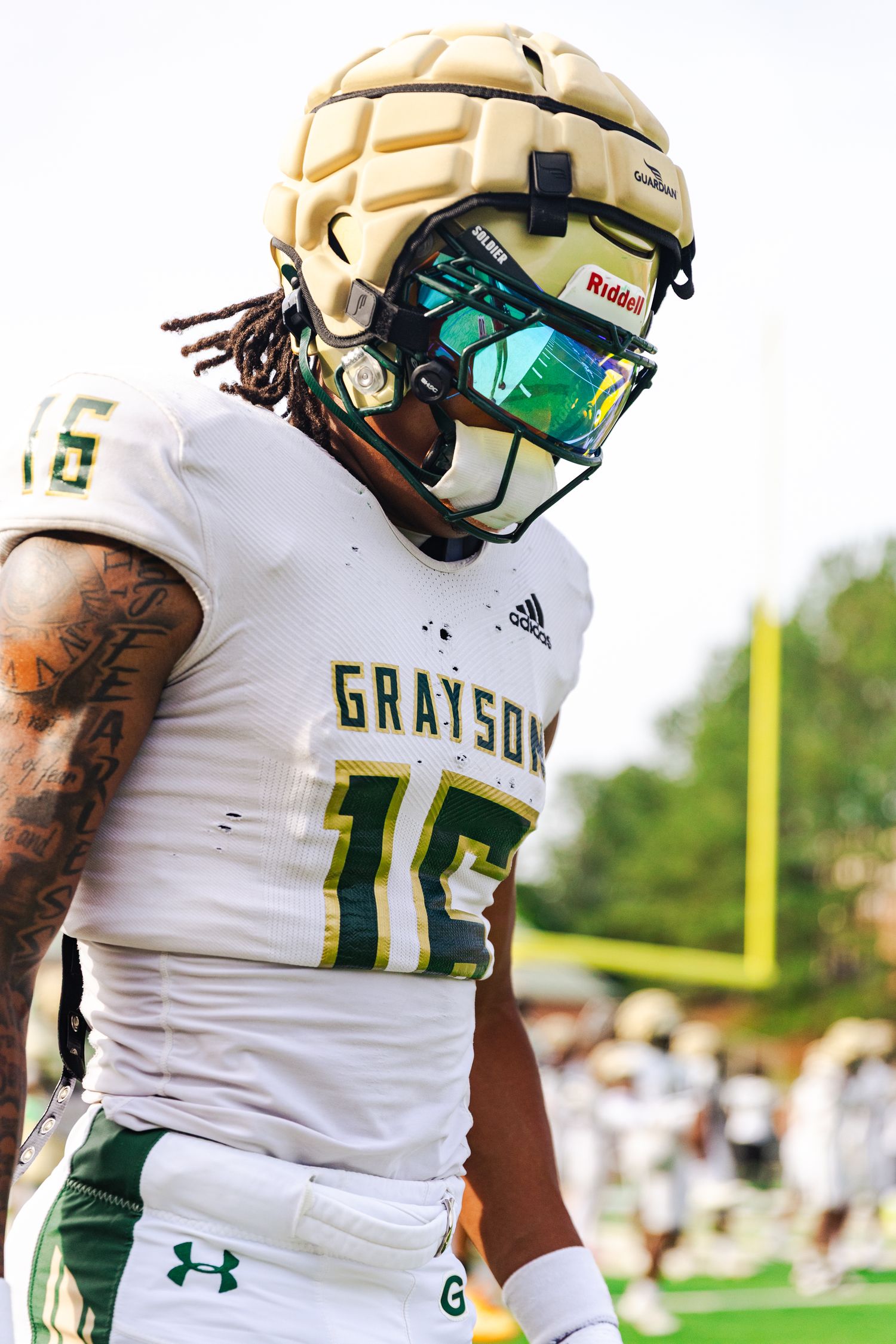 Football player in white Grayson jersey with reflective visor helmet.